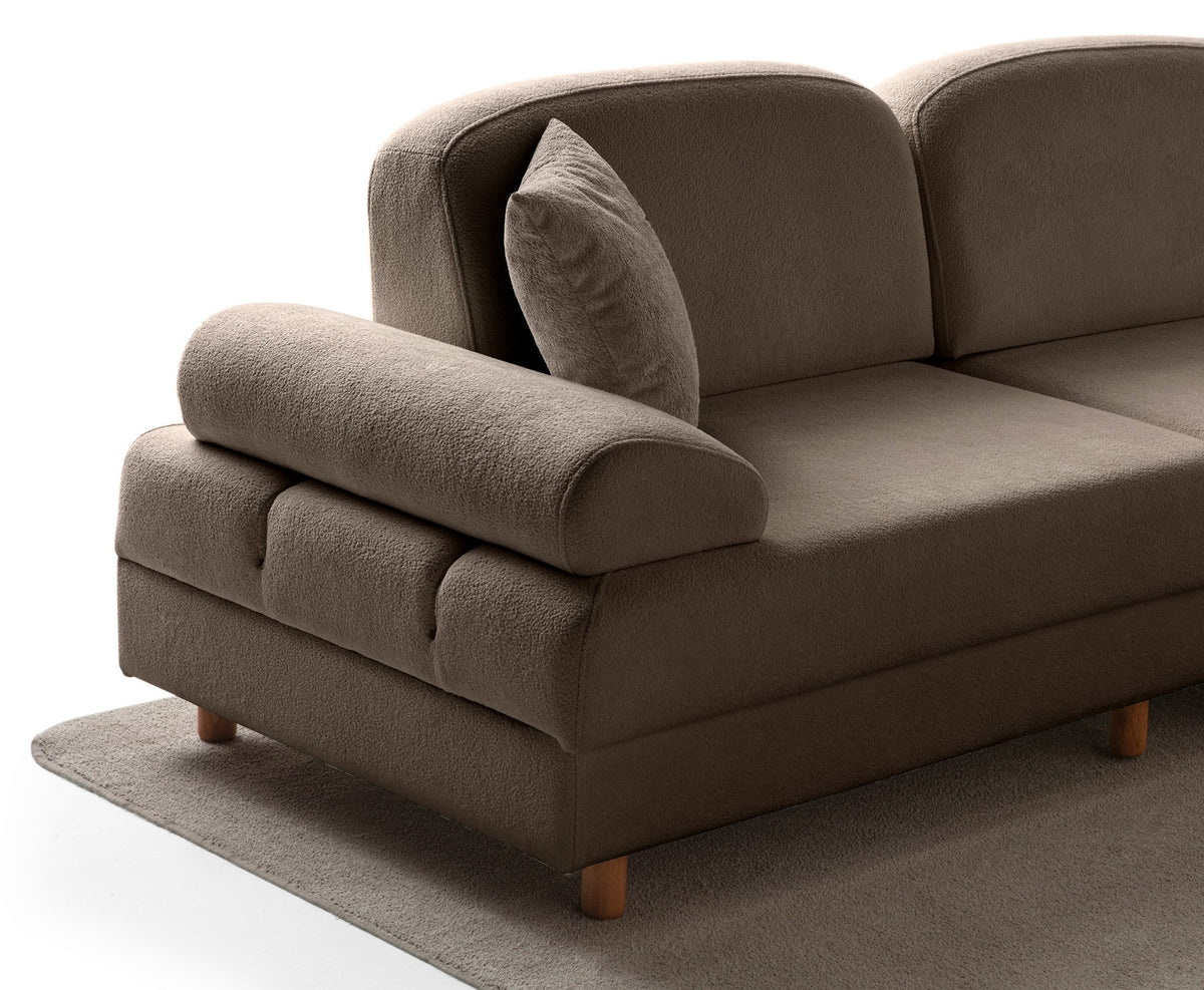 Braunes Eck-Schlafsofa Aries Modular M mit Coco-Boucle-Stoffbezug, Holzbeinen und sichtbarer Truhe, im Wohnzimmer aufgestellt.