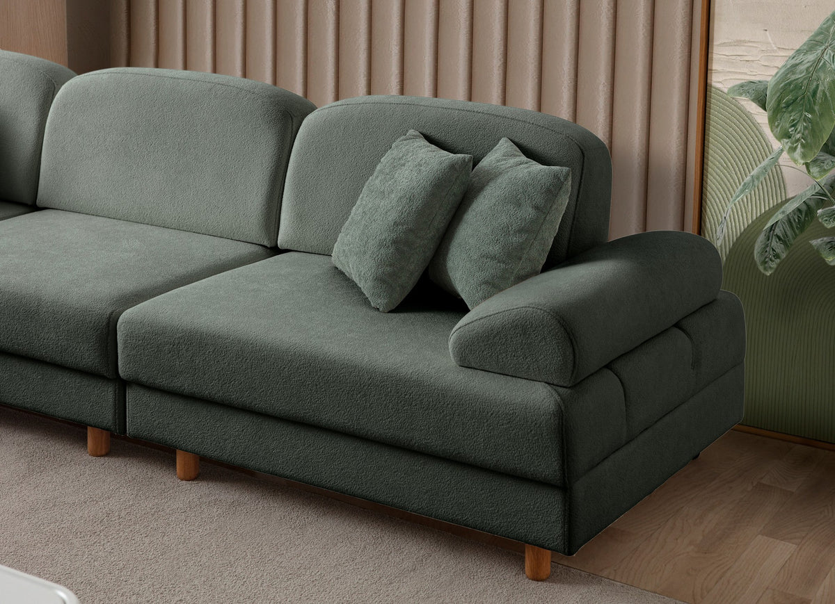 Grünes Eck-Schlafsofa Aries Modular M von Hanah Home mit Coco-Boucle-Polyesterbezug, Holzbeinen und sechs Zierkissen im Wohnzimmer.