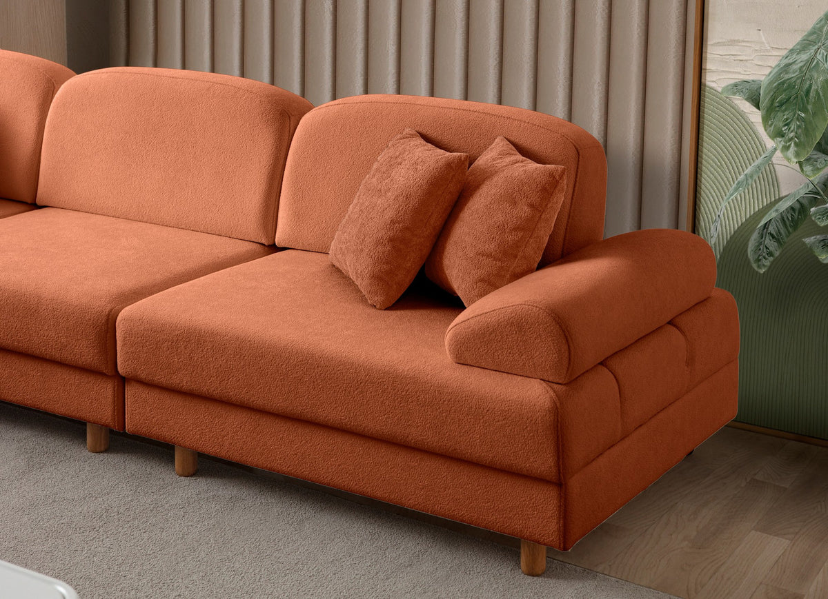 Orangefarbenes Eck-Schlafsofa Aries Modular M mit Coco-Boucle-Stoff, Holzbeinen und sechs Kissen, aufgenommen in einem Wohnraum.