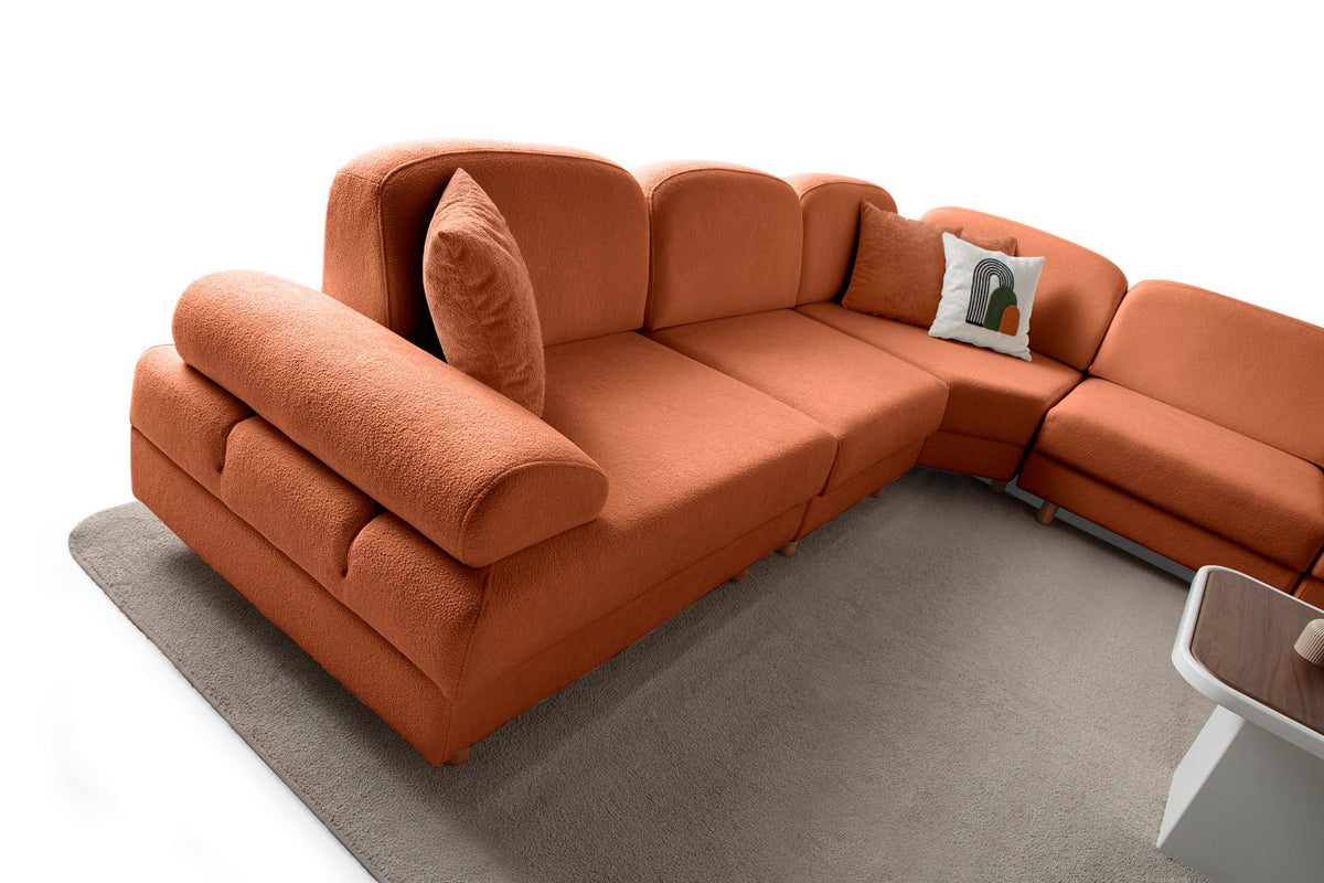 Orangefarbenes Eck-Schlafsofa Aries Modular M mit Coco-Boucle-Stoff, Holzbeinen und sechs Kissen, aufgenommen in einem Wohnraum.