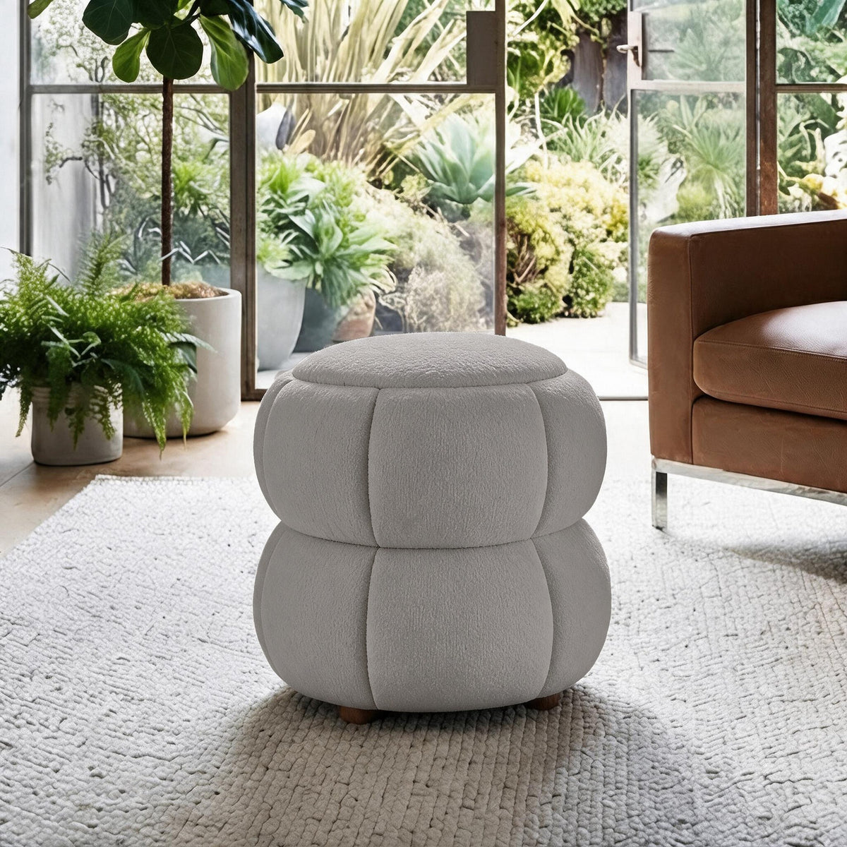 Runder Pouf in Hellgrau mit gestricktem Polyesterbezug, Holzkugelfüssen und gepolstertem Sitzbereich auf hellem Hintergrund fotografiert.