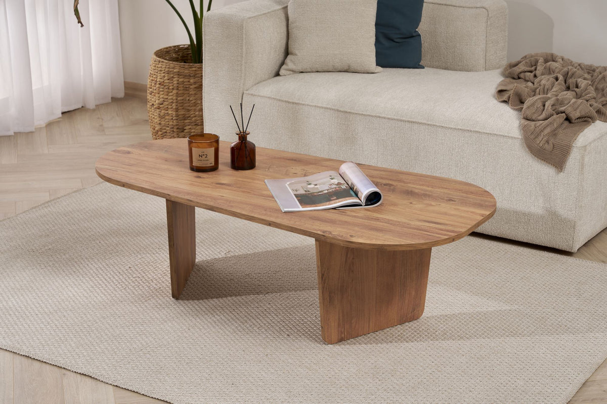 Ovaler Couchtisch in Atlantik-Kiefer Optik von Nordure aus melaminbeschichteter Spanplatte, 130 cm breit, 65 cm tief, 40 cm hoch, im Wohnraum platziert.