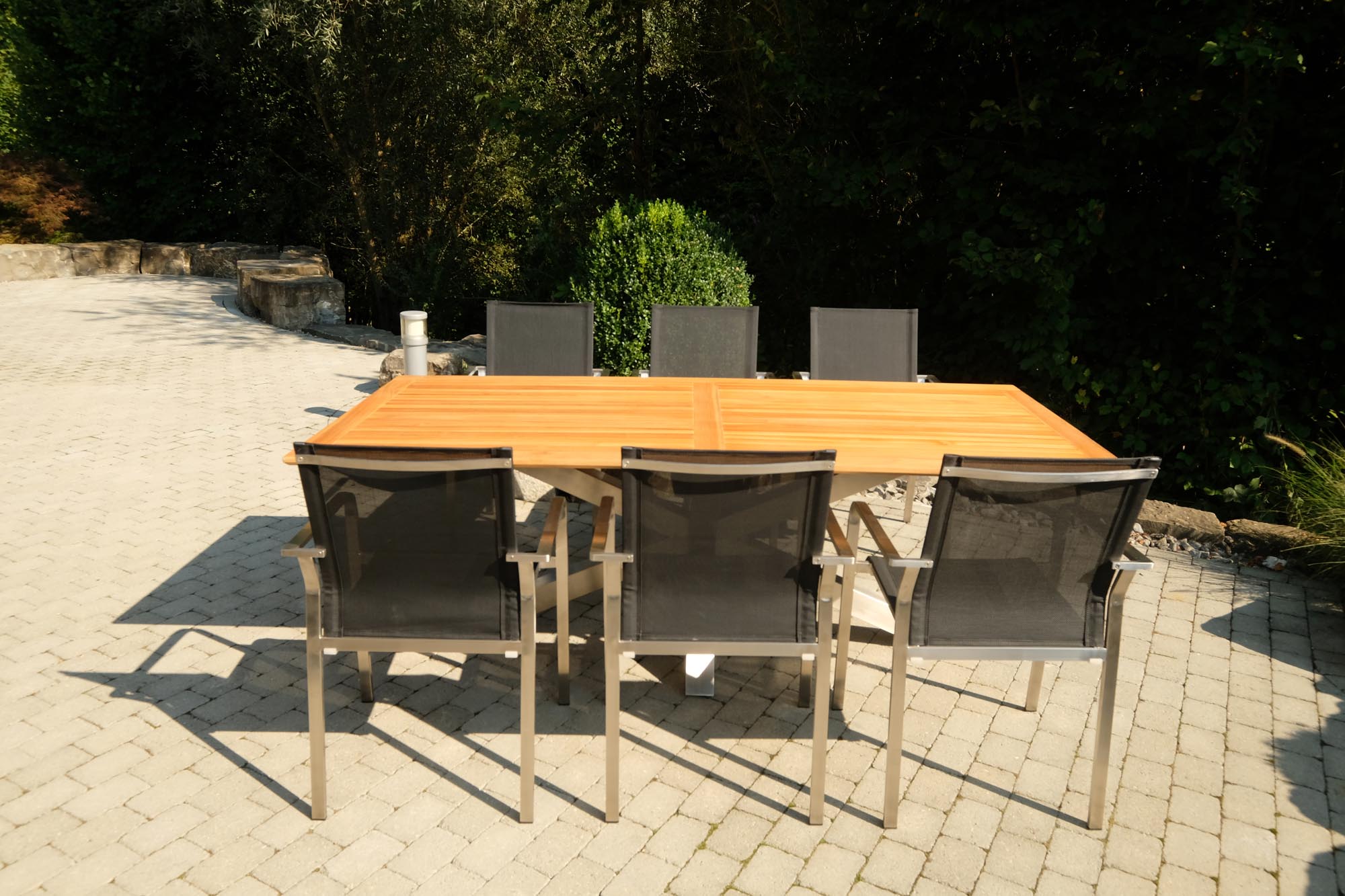 Moderner Gartentisch Monaco mit robusten XX-Füßen und edler Teakplatte, perfekt für gemütliche Stunden im Freien.