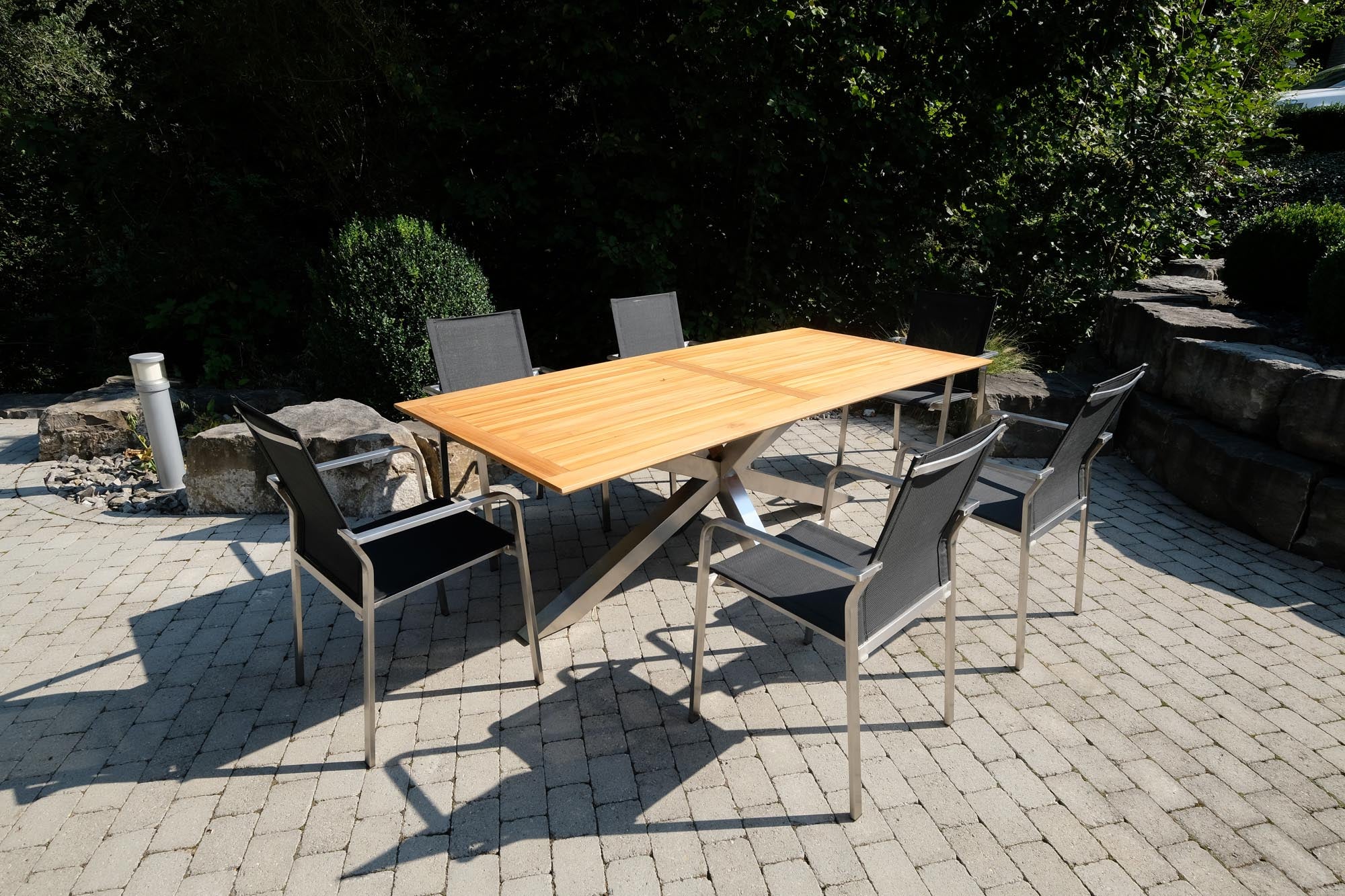 Eleganter Gartentisch Monaco mit stabilen XX-Füßen und hochwertiger Teakplatte, ideal für stilvolle Outdoor-Entspannung.