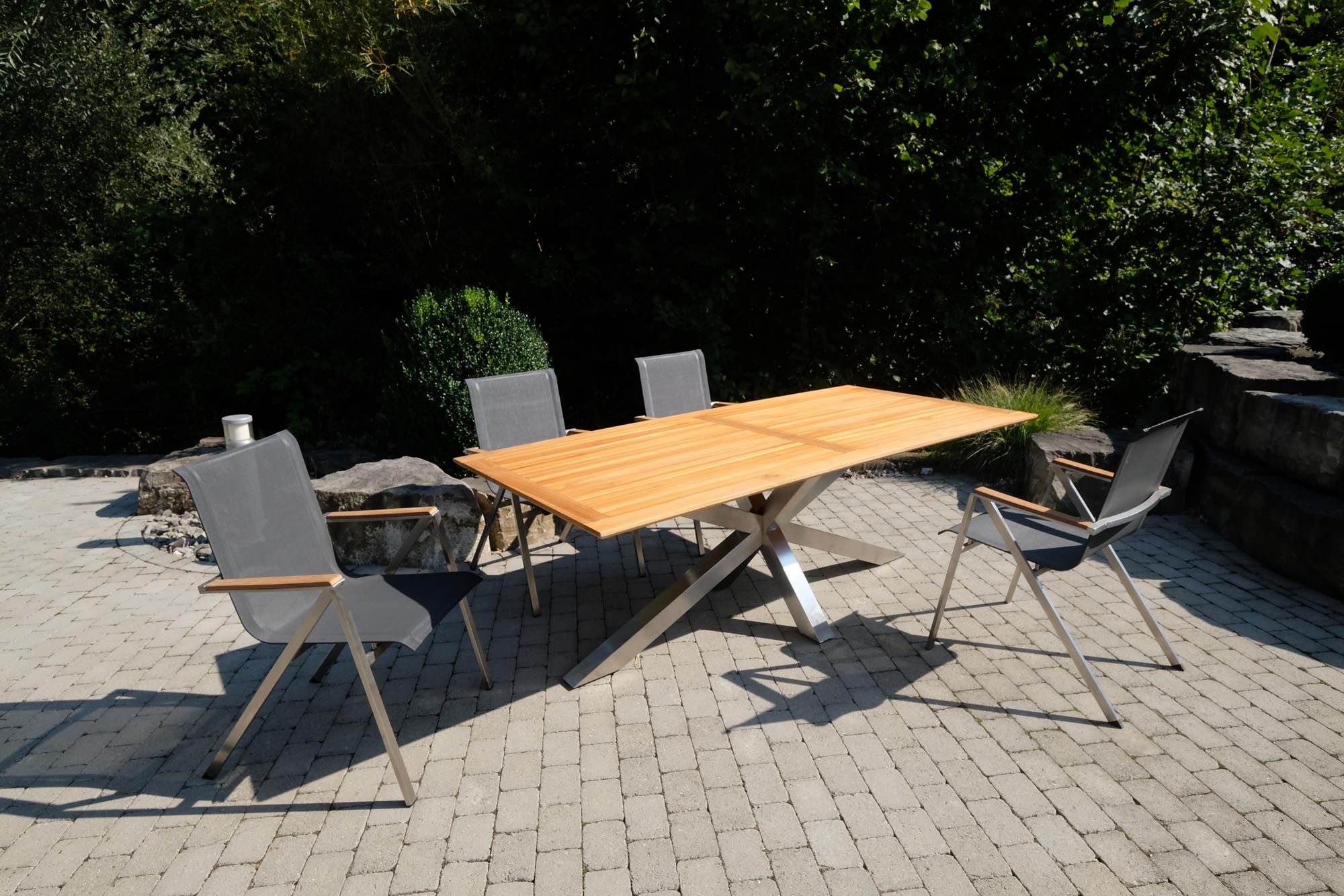 Moderner Gartentisch Monaco mit robusten XX-Füßen und edler Teakplatte, perfekt für gemütliche Stunden im Freien.
