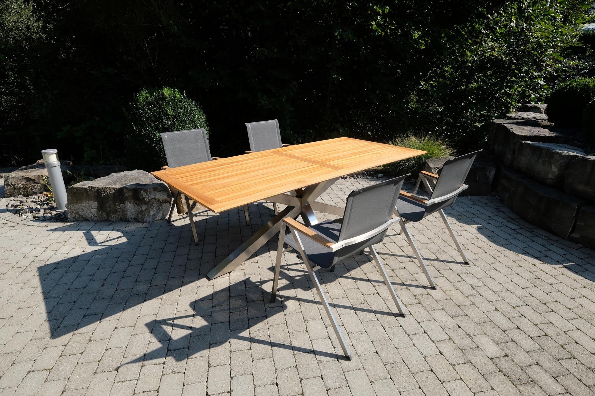 Eleganter Gartentisch Monaco mit stabilen XX-Füßen und hochwertiger Teakplatte, ideal für stilvolle Outdoor-Entspannung.