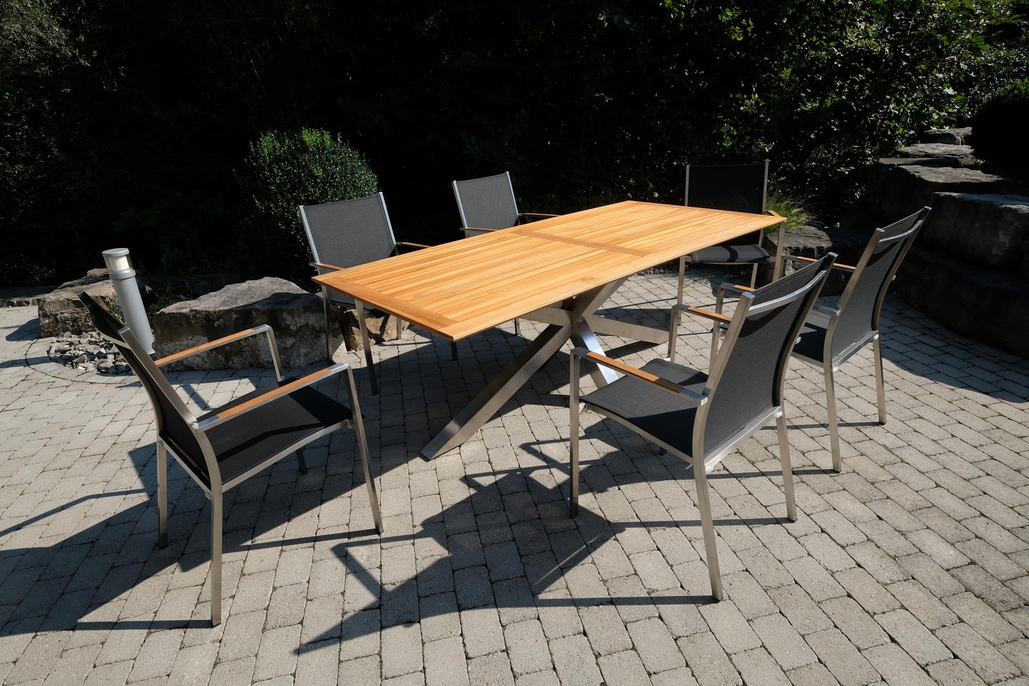 Eleganter Gartentisch Monaco mit stabilen XX-Füßen und hochwertiger Teakplatte, ideal für stilvolle Outdoor-Entspannung.