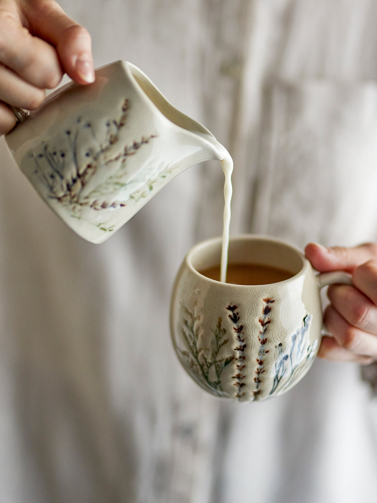 Weisse Tasse Bea aus Steingut mit zartem Blumenmuster und feiner Krakeleeglasur