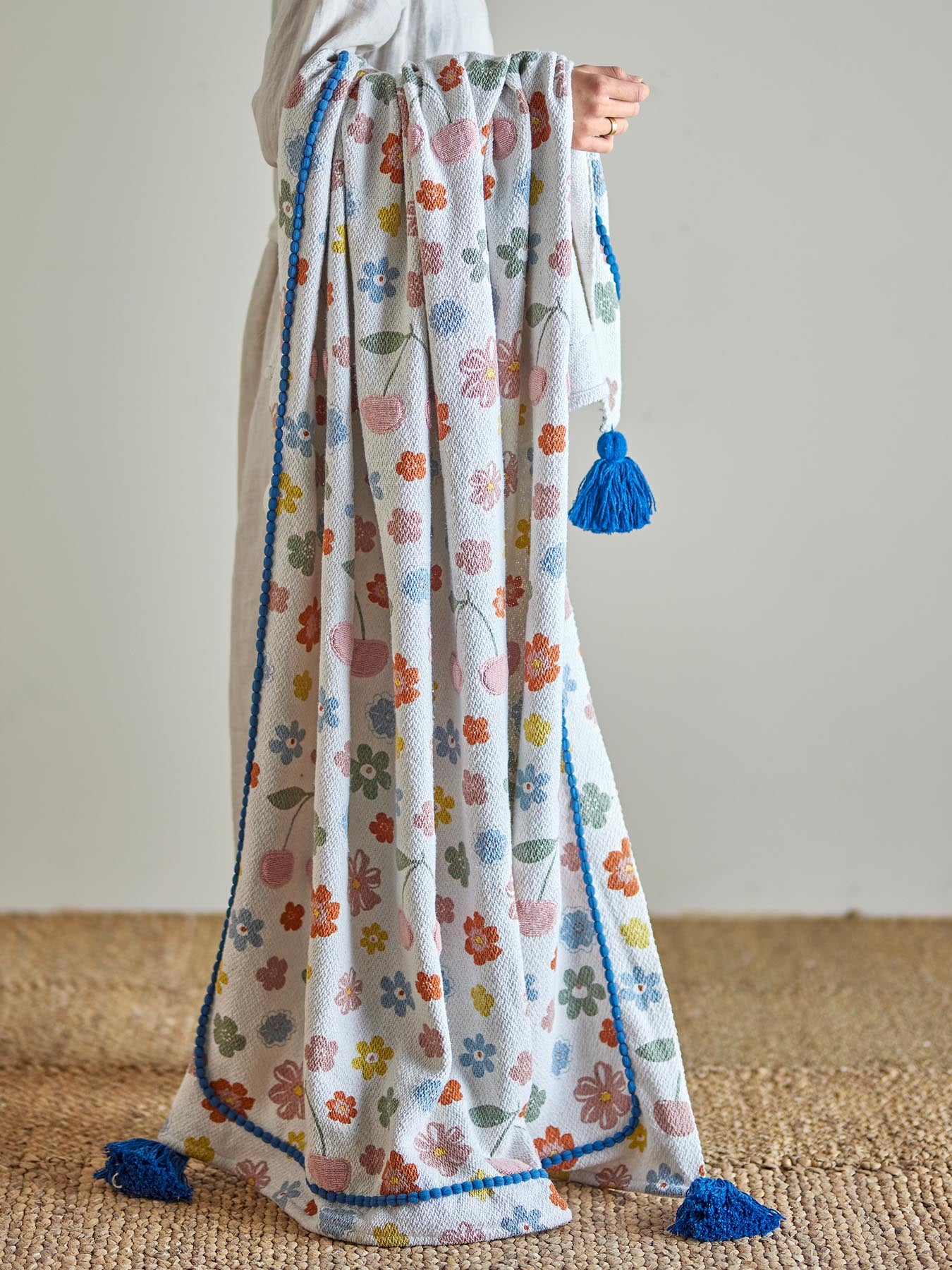 Entdecken Sie die Cherry Decke von Bloomingville Mini – eine umweltfreundliche Kuscheldecke aus recycelter Baumwolle mit charmantem Kirschdesign in Rosatönen.