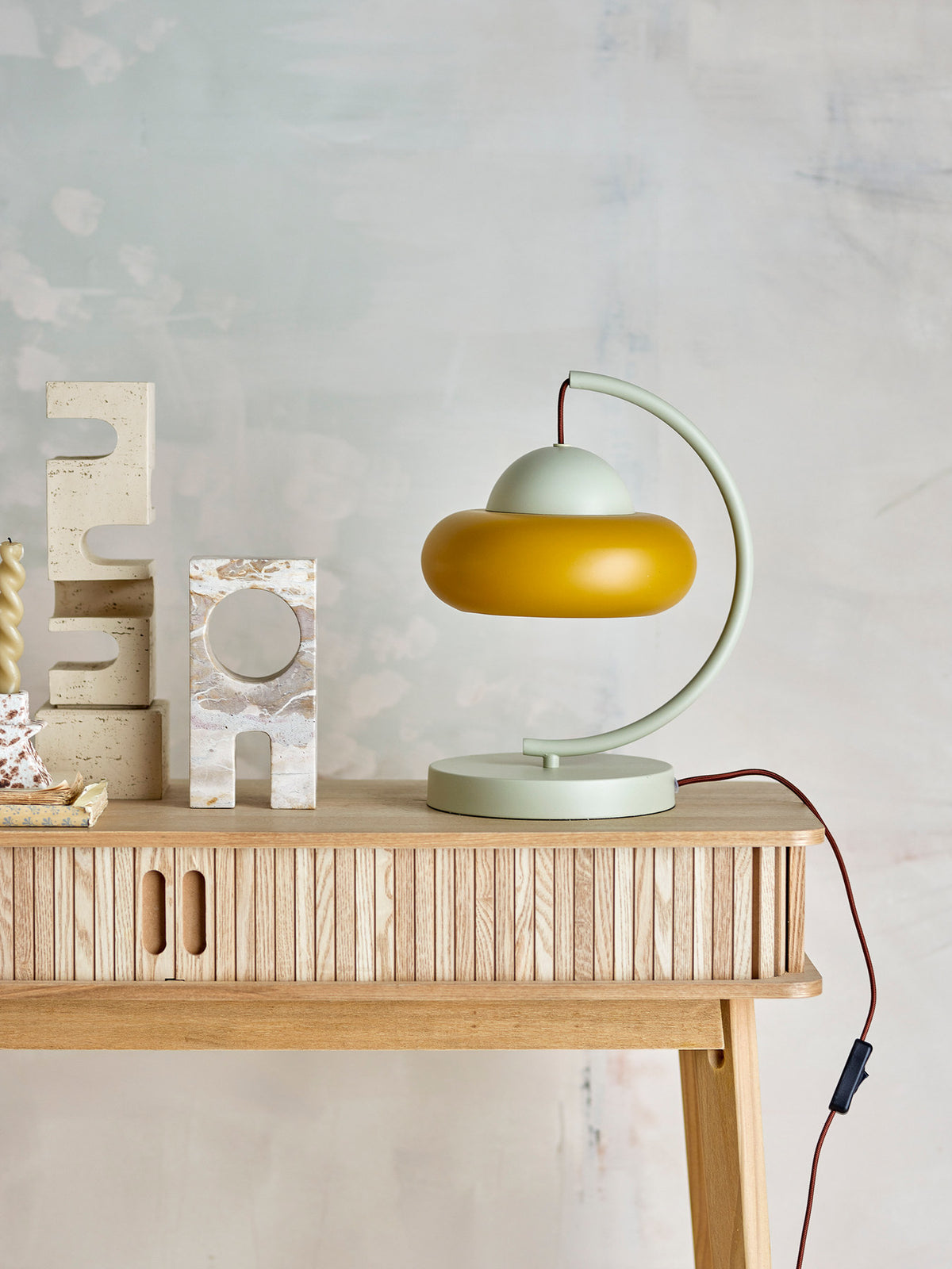 Weisse Bubble Tischlampe aus Eisen von Bloomingville mit geschwungenem Arm und rundem Lampenschirm, braunes Kabel sichtbar, skulpturale Form