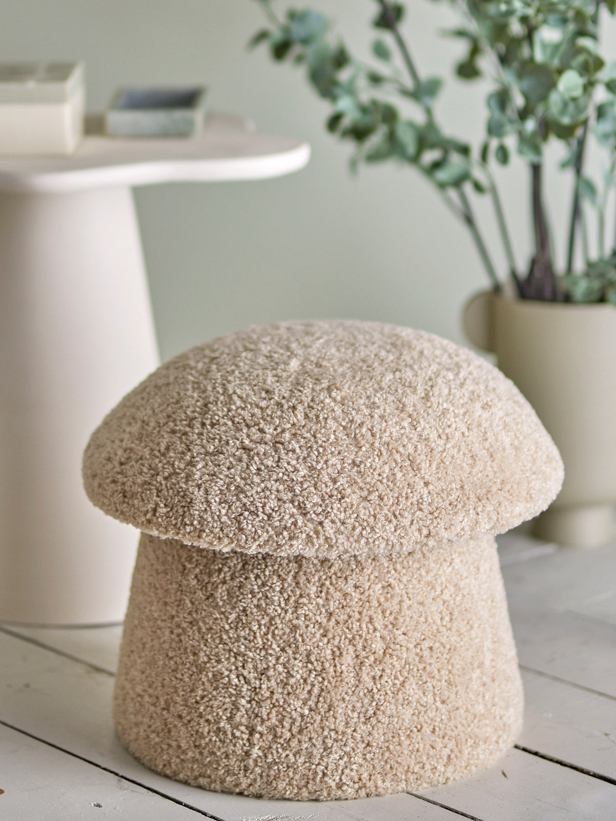 Runder Pouf in Beige mit strukturierter Polyester-Oberfläche und Beinen aus Kiefernholz, breite Oberseite über schmalerem Fuss.