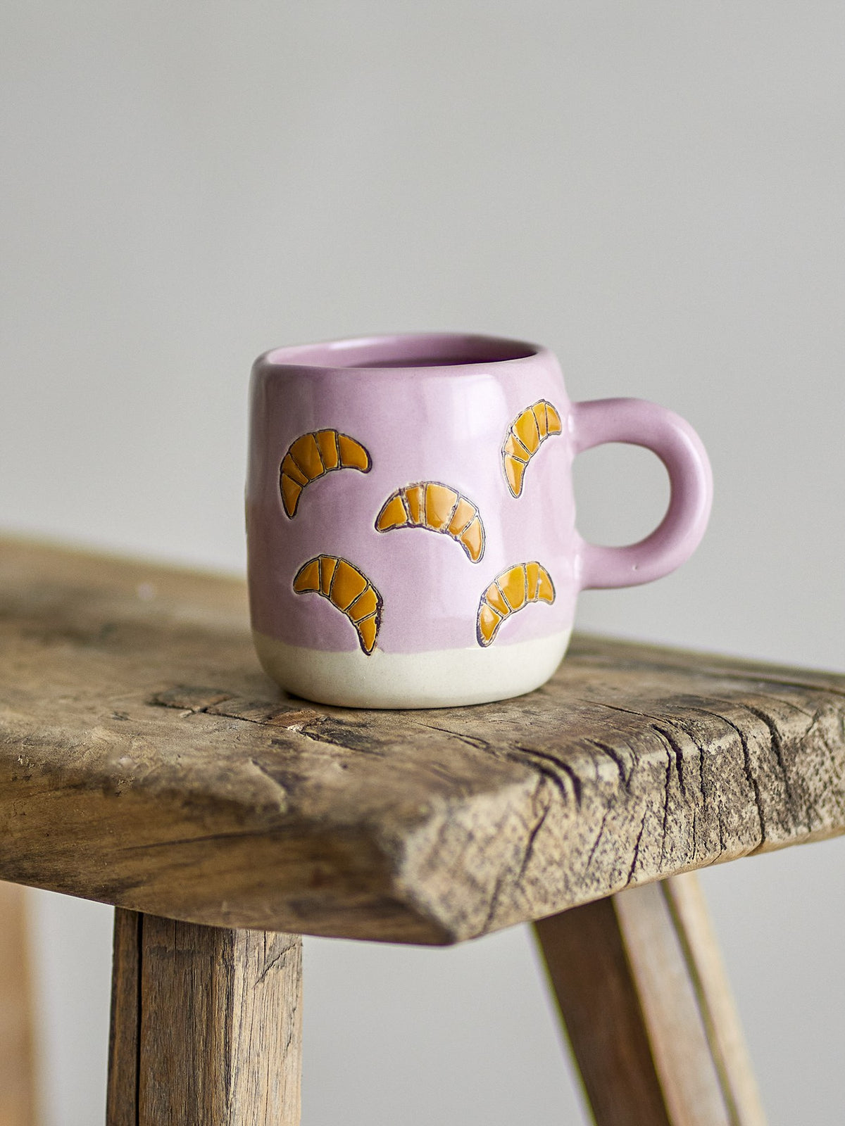 Millie Tasse von Bloomingville Mini aus Steingut, handbemalt mit Croissant-Motiven in Orange, Beige und Grün, kleine runde Form.