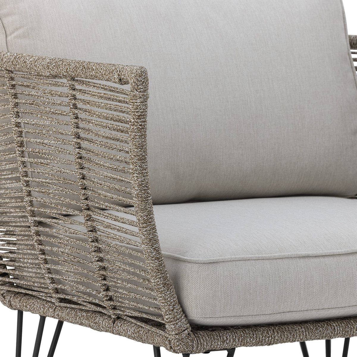 Brauner Loungesessel mit schwarzem Eisengestell, Flechtoptik und hellen Kissen, Outdoor-Sessel im Freien fotografiert.