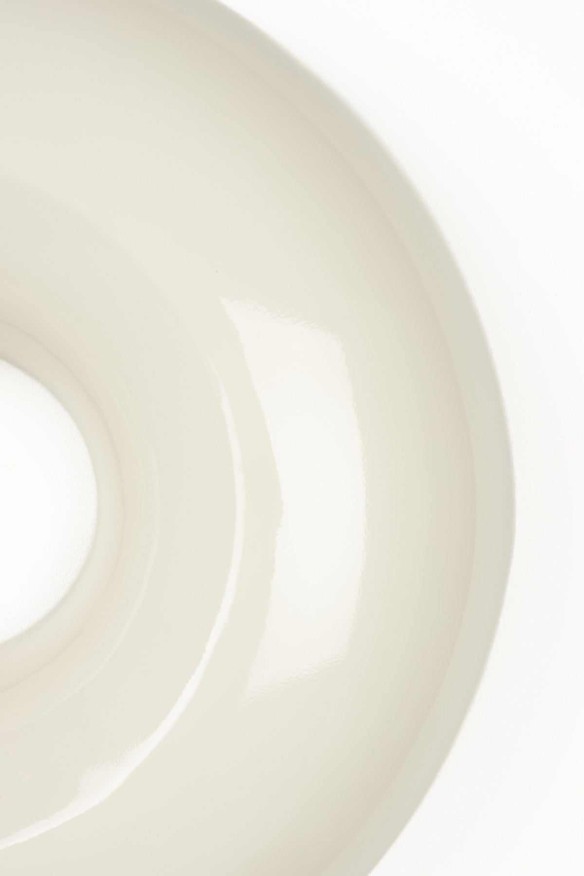 Runde beige Wandleuchte aus glänzendem Metall in Donut-Form mit indirektem Lichtaustritt entlang des Randes, montiert an einer Wand.
