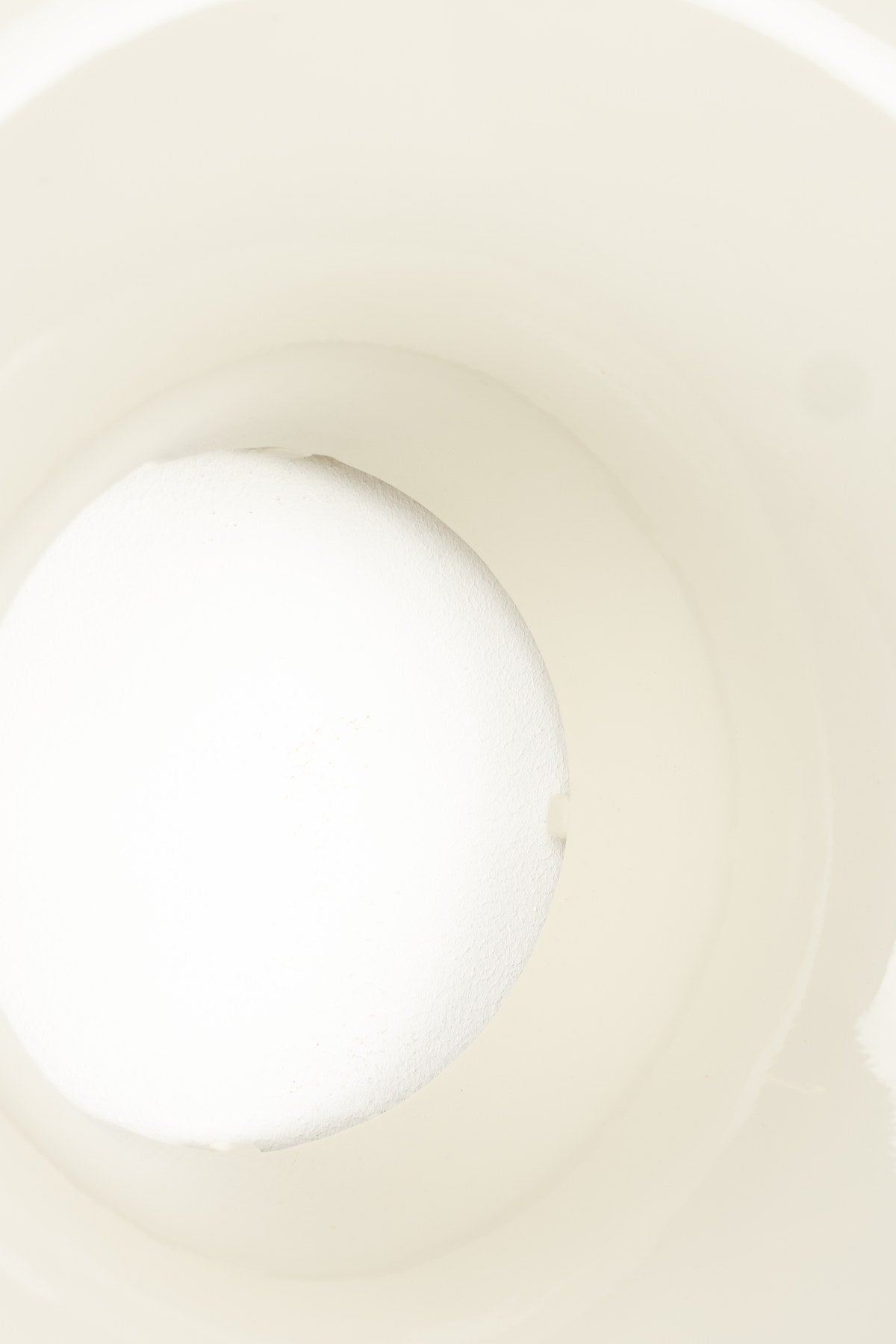 Runde beige Wandleuchte aus glänzendem Metall in Donut-Form mit indirektem Lichtaustritt entlang des Randes, montiert an einer Wand.