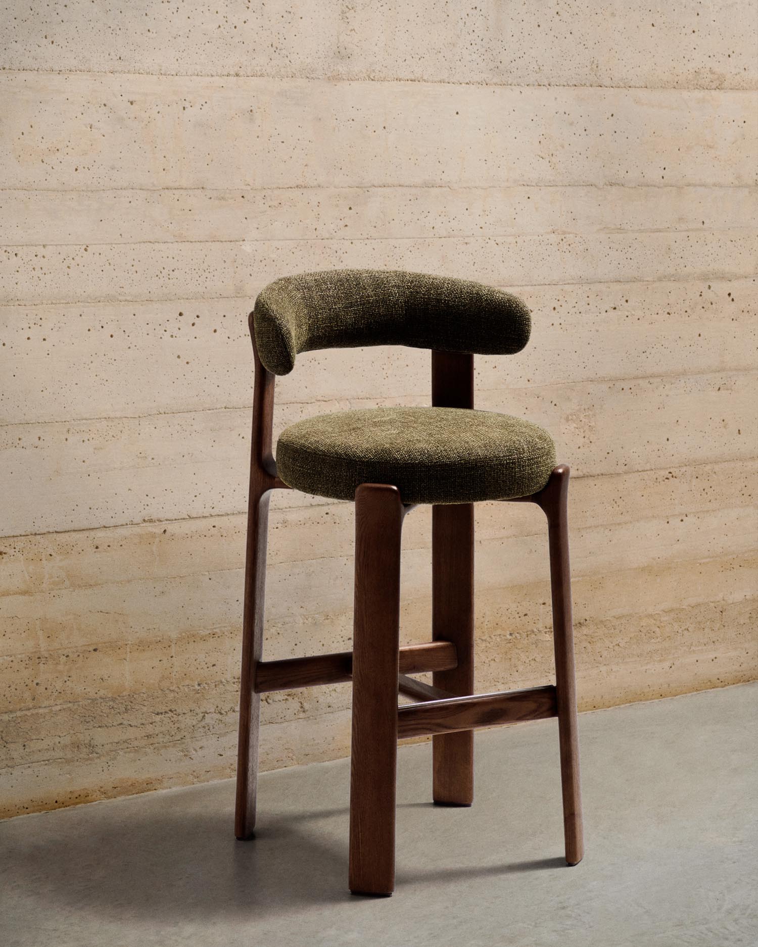 Entdecken Sie den Hocker Granite von Kave Home: Ein stilvoller Barhocker aus grünem Chenille und FSC-zertifiziertem Eschenholz, 75 cm hoch.