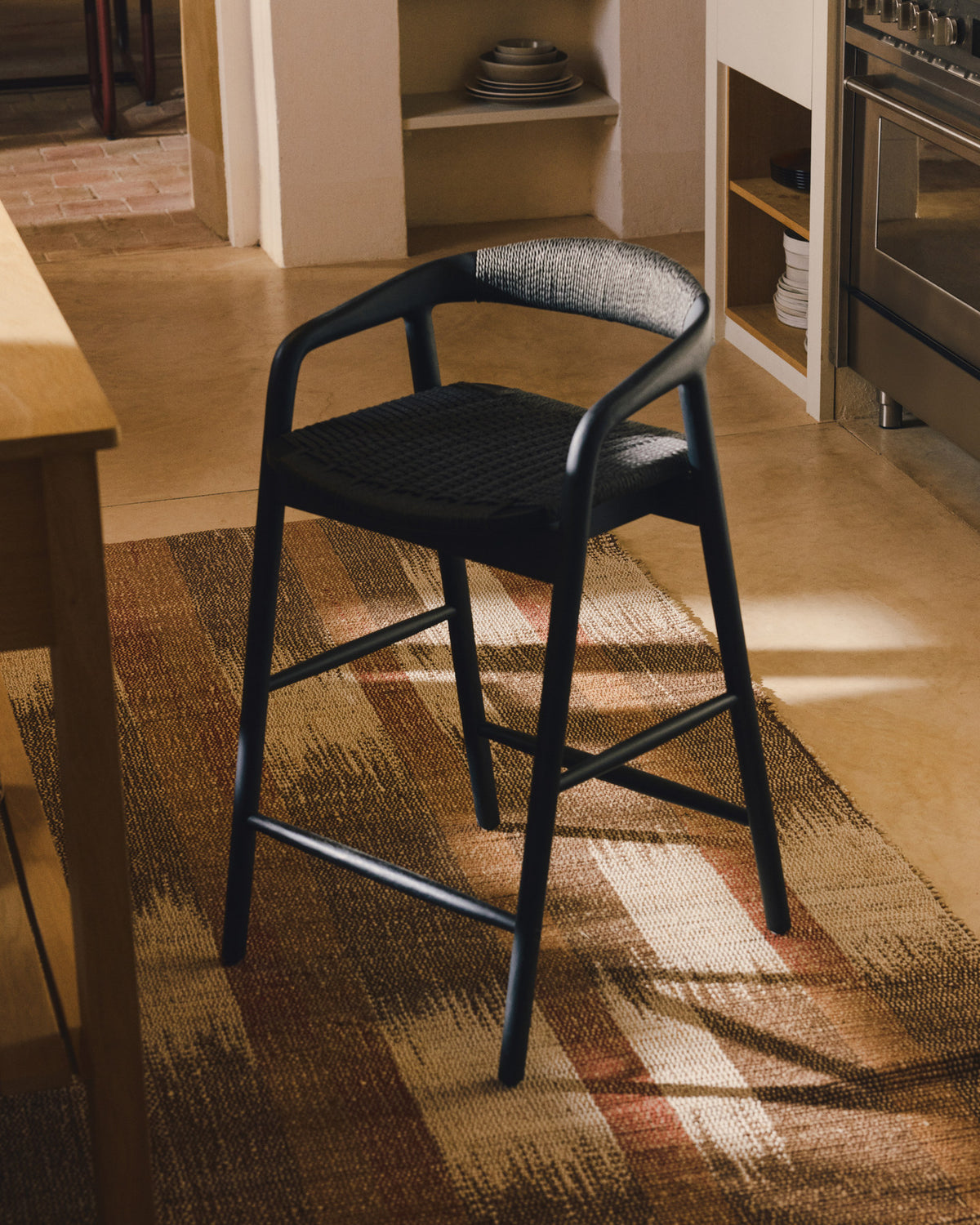 Hocker Derile aus massivem Eichenholz mit schwarzem Finish und schwarzem Papierseil FSC Mix Credit 65 cm in Schwarz präsentiert im Onlineshop von KAQTU Design AG. Barstuhl mit Armlehne ist von Kave Home