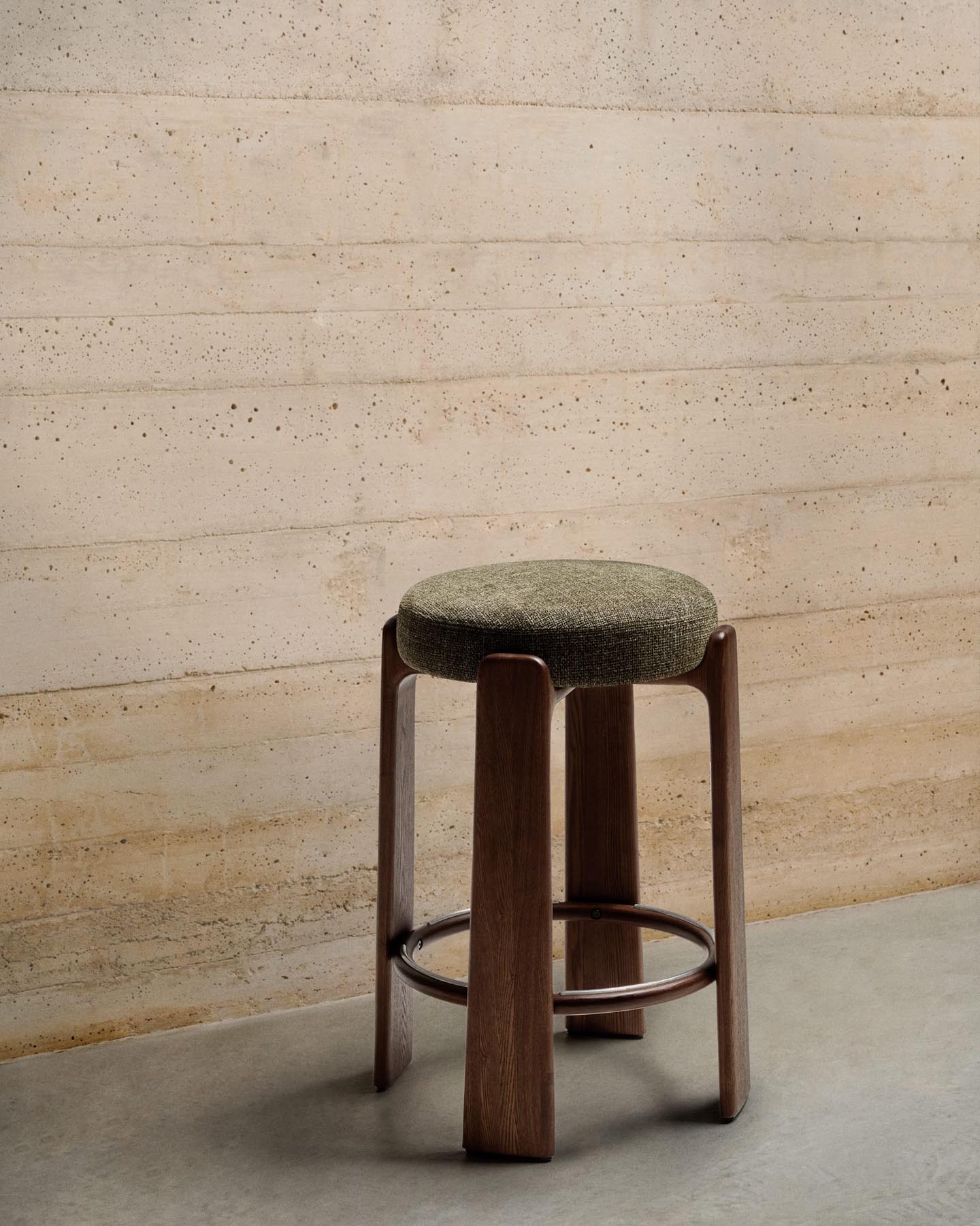 Entdecken Sie den Hocker Granite von Kave Home: stilvoller Hocker aus grüner Chenille und FSC-zertifiziertem Eschenholz mit nussbaumfarbenem Finish.