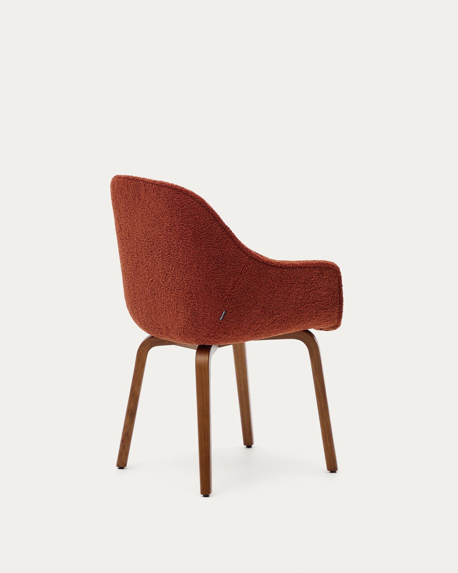 Der Aleli Stuhl in warmem Terrakotta-Bouclé und stabilen Eschenholzbeinen mit Nussholz-Finish bietet eleganten Komfort für jedes Zuhause.