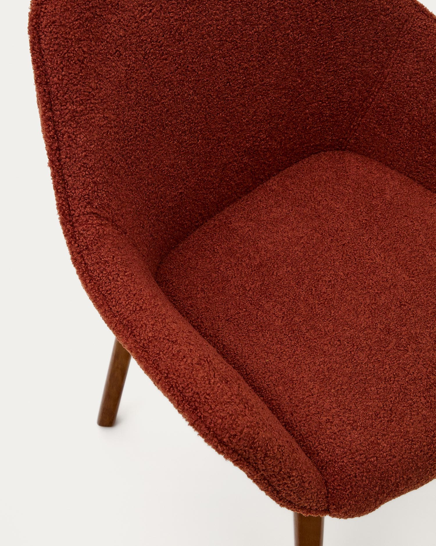 Moderner Aleli Stuhl in einladendem Terrakotta-Bouclé, mit robusten Eschenholzbeinen und edlem Nussholz-Finish – perfekt für jedes Zuhause.