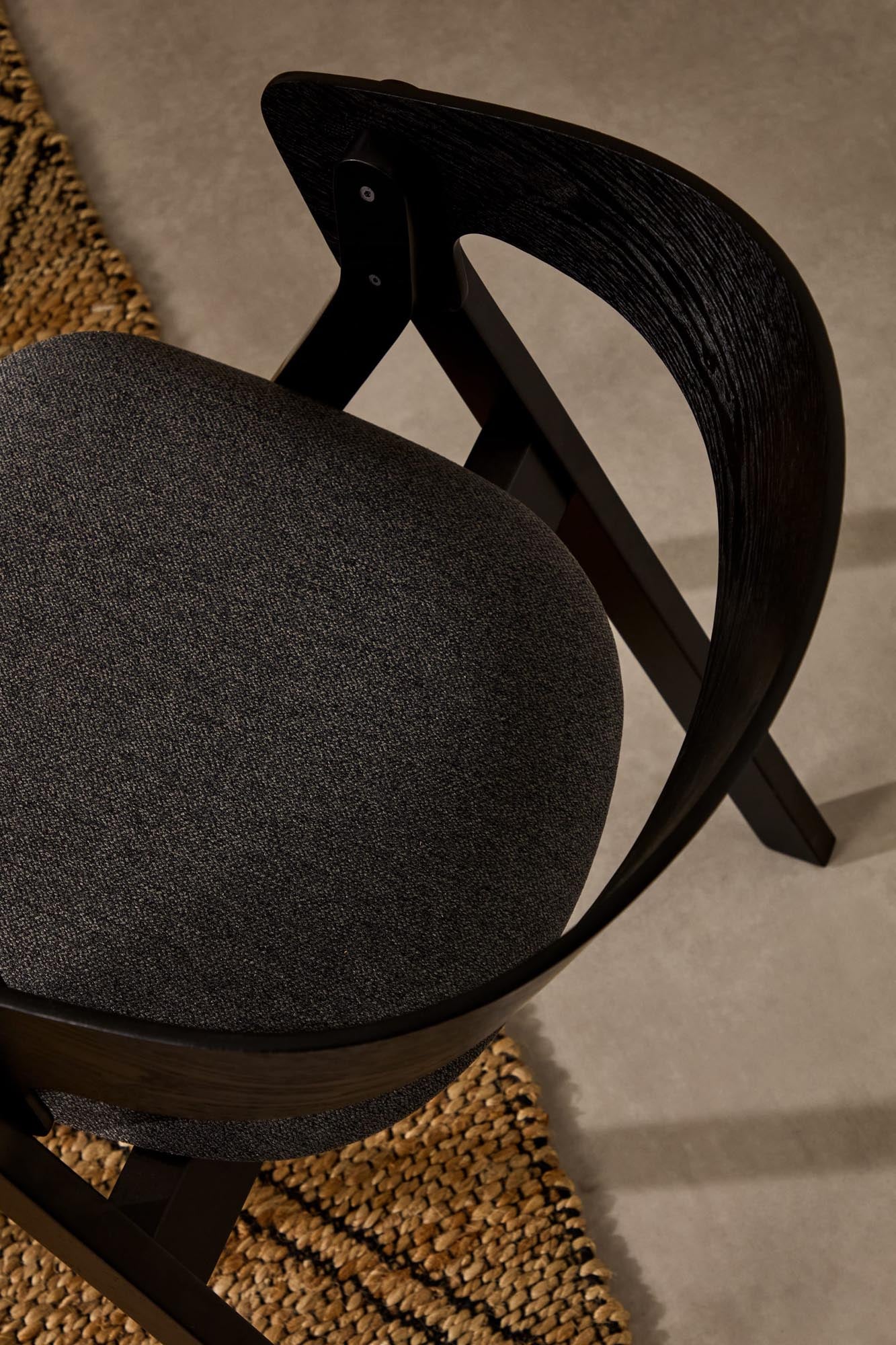 Der Stuhl Godia von Kave Home kombiniert elegantes Eschefurnier und robustes Kautschukholz mit einem stilvollen schwarzen Finish und grauer Chenille für höchsten Sitzkomfort.