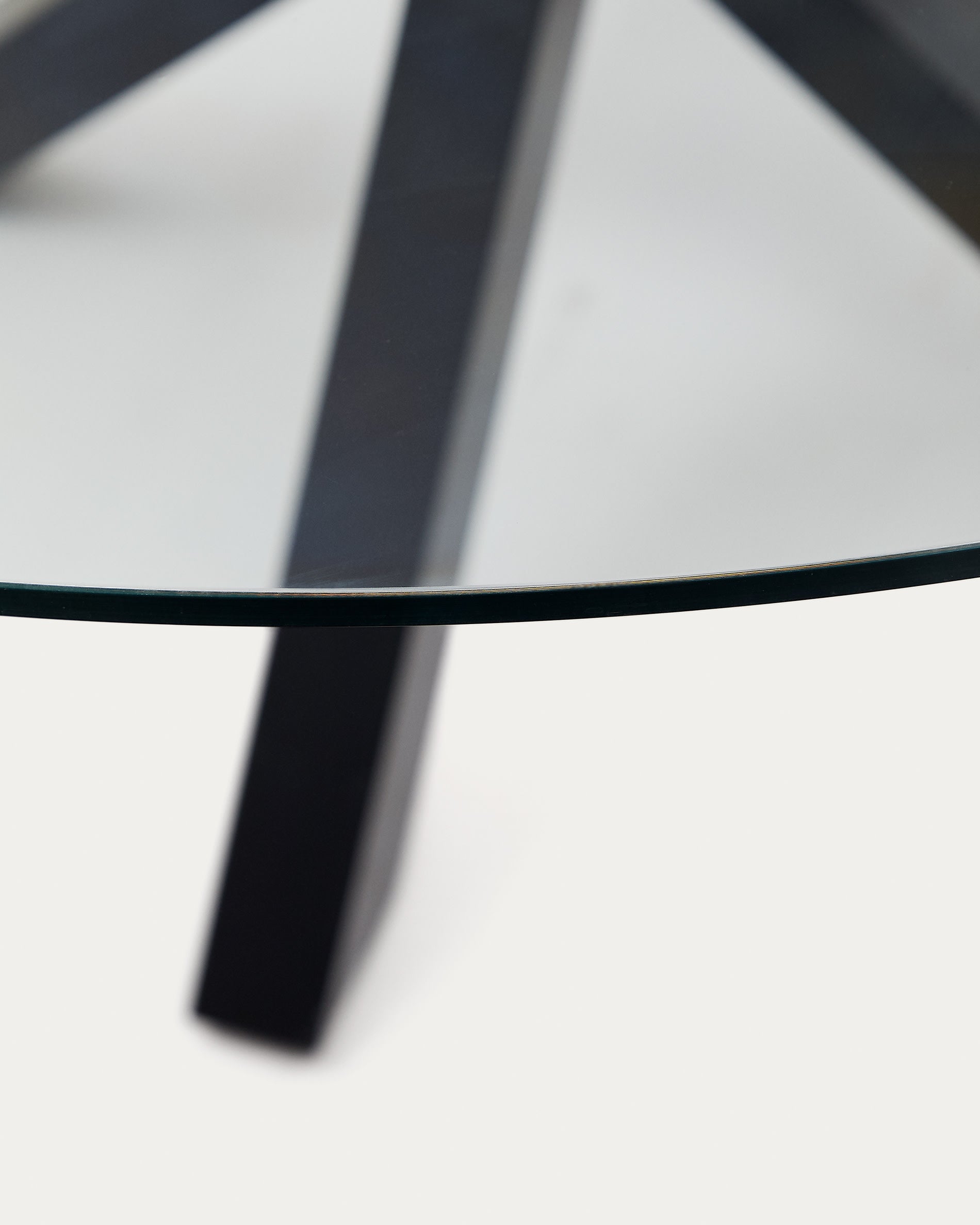 Entdecken Sie den stilvollen Tisch Argo von Kave Home: Ø 150 cm, elegante Glasoberfläche, stabile schwarze Stahlbeine – perfekt für gesellige Anlässe.