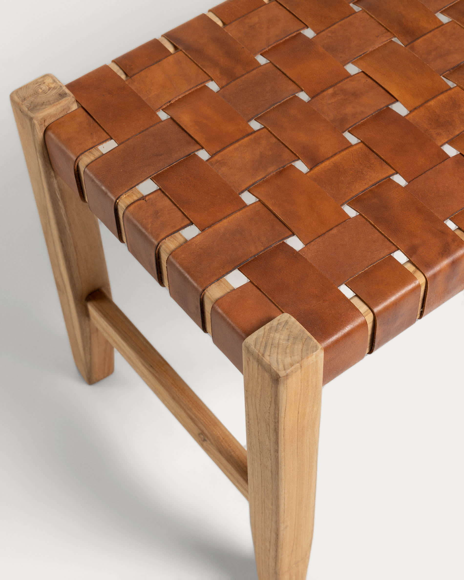 Die Calixta Bank von Kave Home aus massivem Teakholz (120 cm) bietet stilvolle Sitzgelegenheit und besticht durch ihre einzigartige Maserung und handgeflochtene Lederriemen.