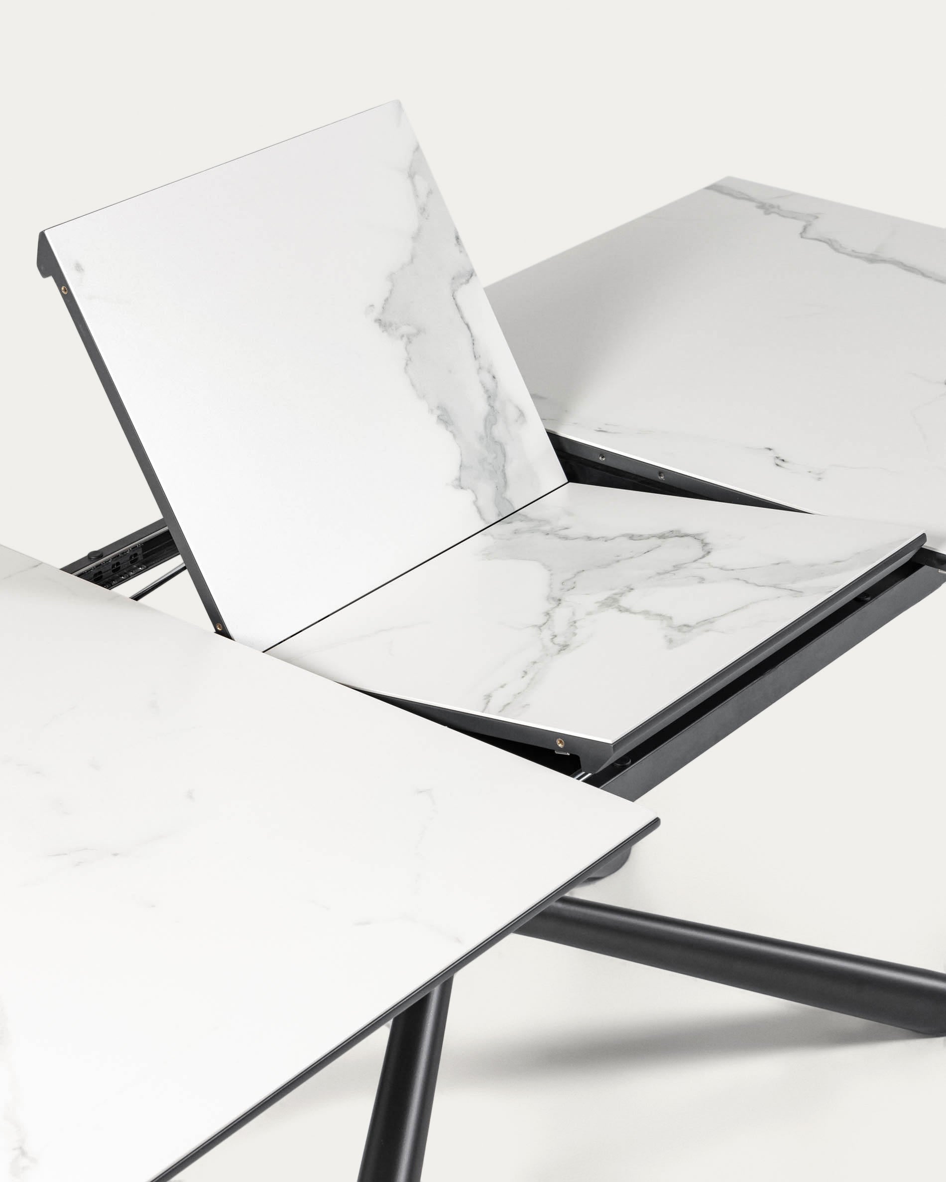 Eleganter, ausziehbarer Tisch mit robuster Weiss Feinsteinzeugplatte und stilvollen schwarzen Stahlbeinen, ideal für jedes Esszimmer.