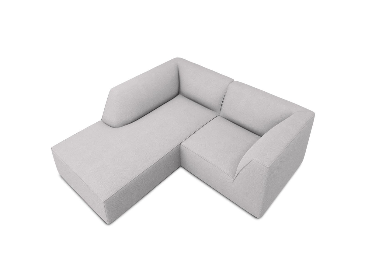 Modulares Ecksofa Siena mit gelbem Ottawa-Stoffbezug, schwarzen Kunststoffbeinen und Récamiere, Ansicht von vorne im Wohnraum.