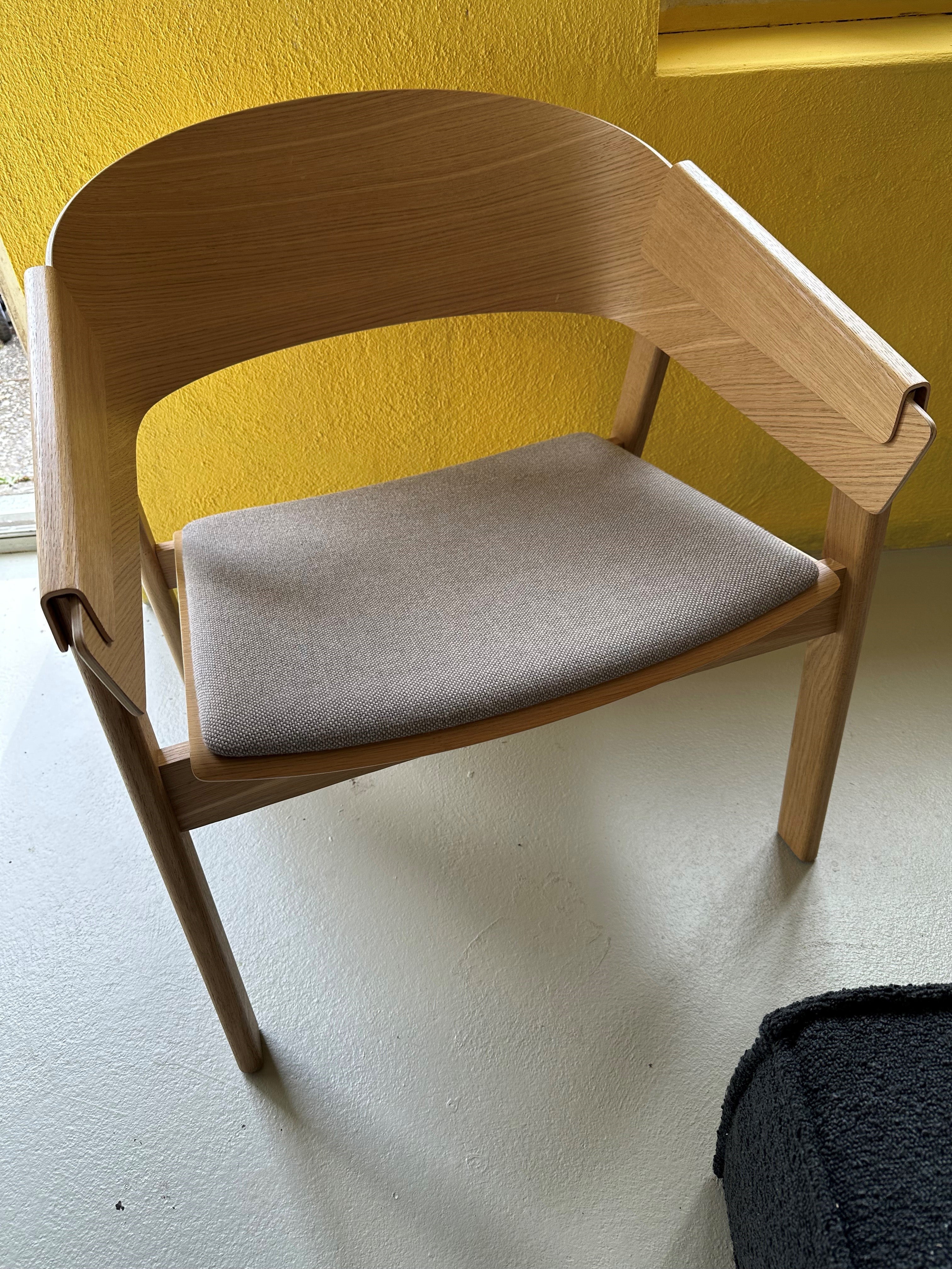 Ein eleganter Loungesessel aus Holz mit minimalistischer Formgebung, geschwungenen Details und einer warmen, natürlichen Ausstrahlung.