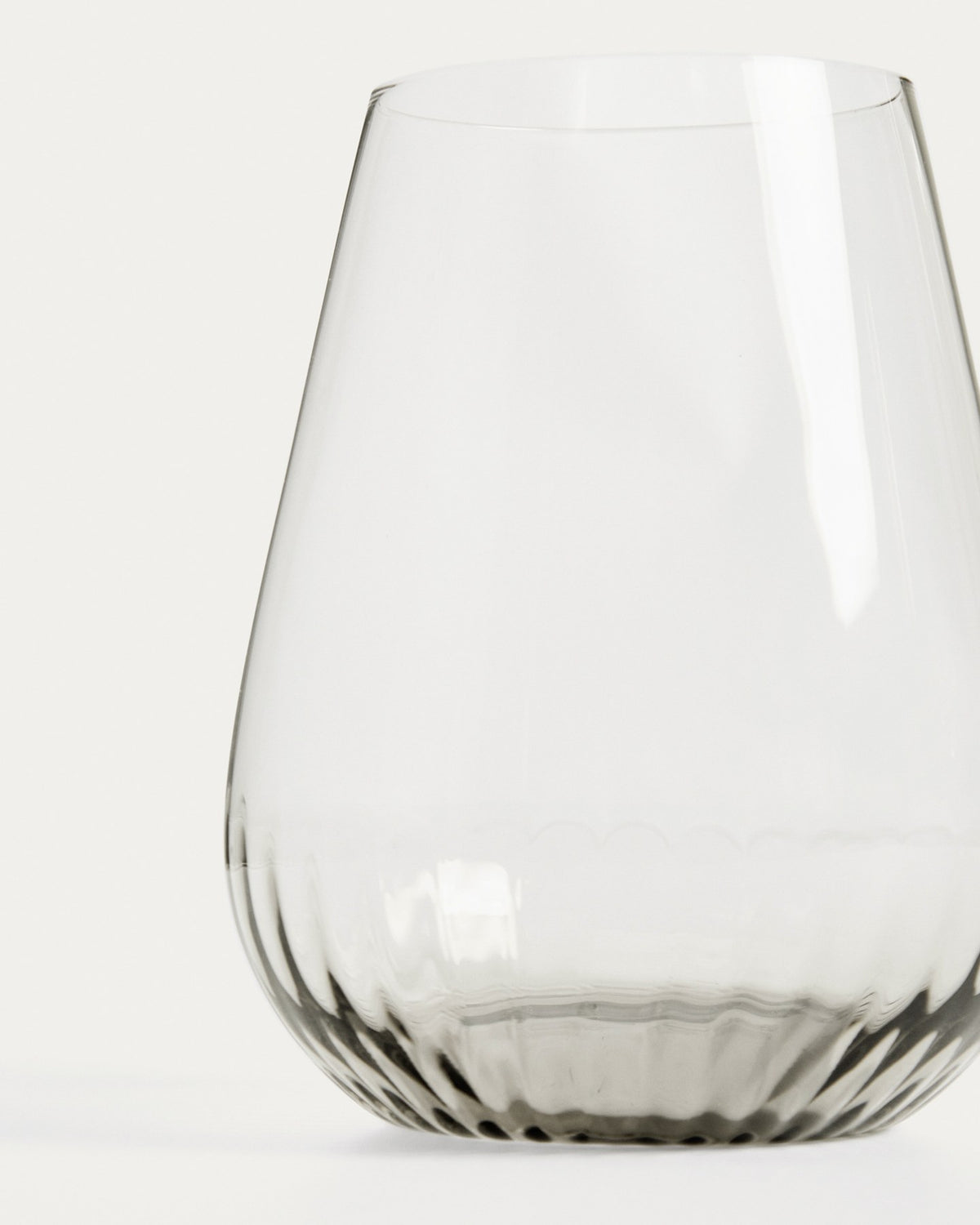 Hellgraues Trinkglas aus 100% Glas mit abgerundeter Basis und grauem Boden, klare Oberfläche, kompakte Form für Getränke.