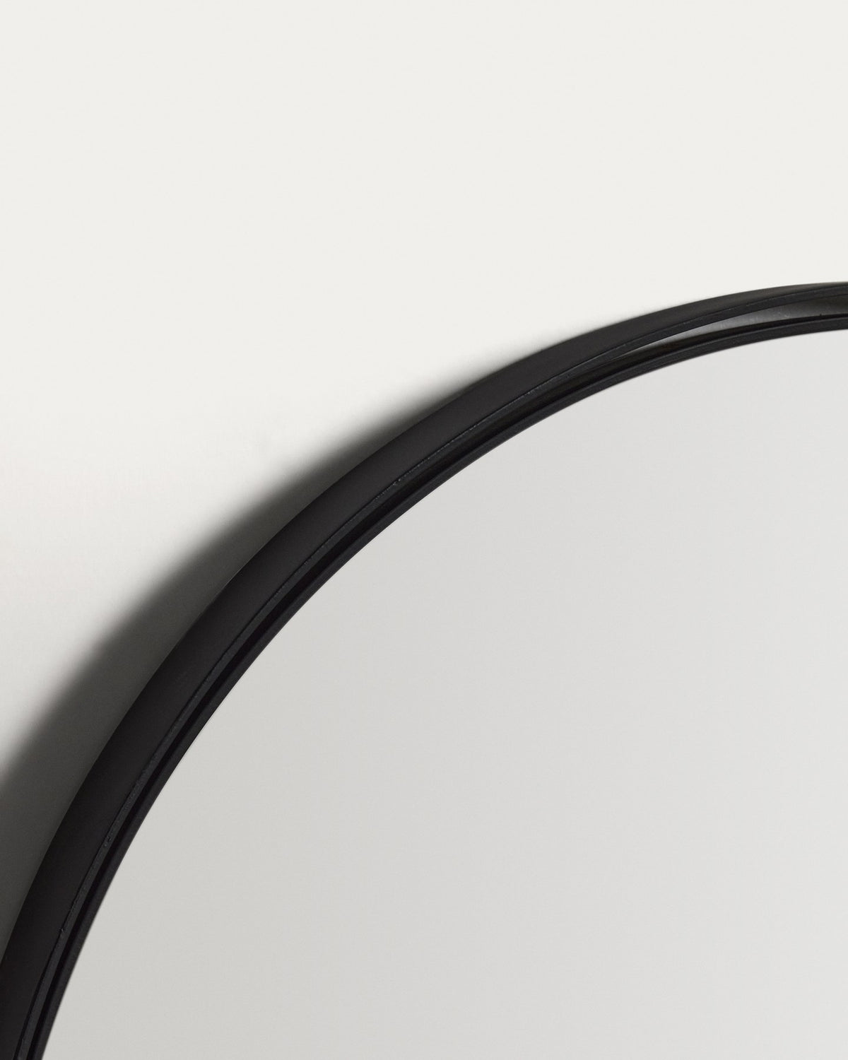 Ovaler Wandspiegel mit schwarzem Metallrahmen aus zwei konzentrischen Ringen, Glasfläche und MDF-Rückseite, an der Wand montiert.