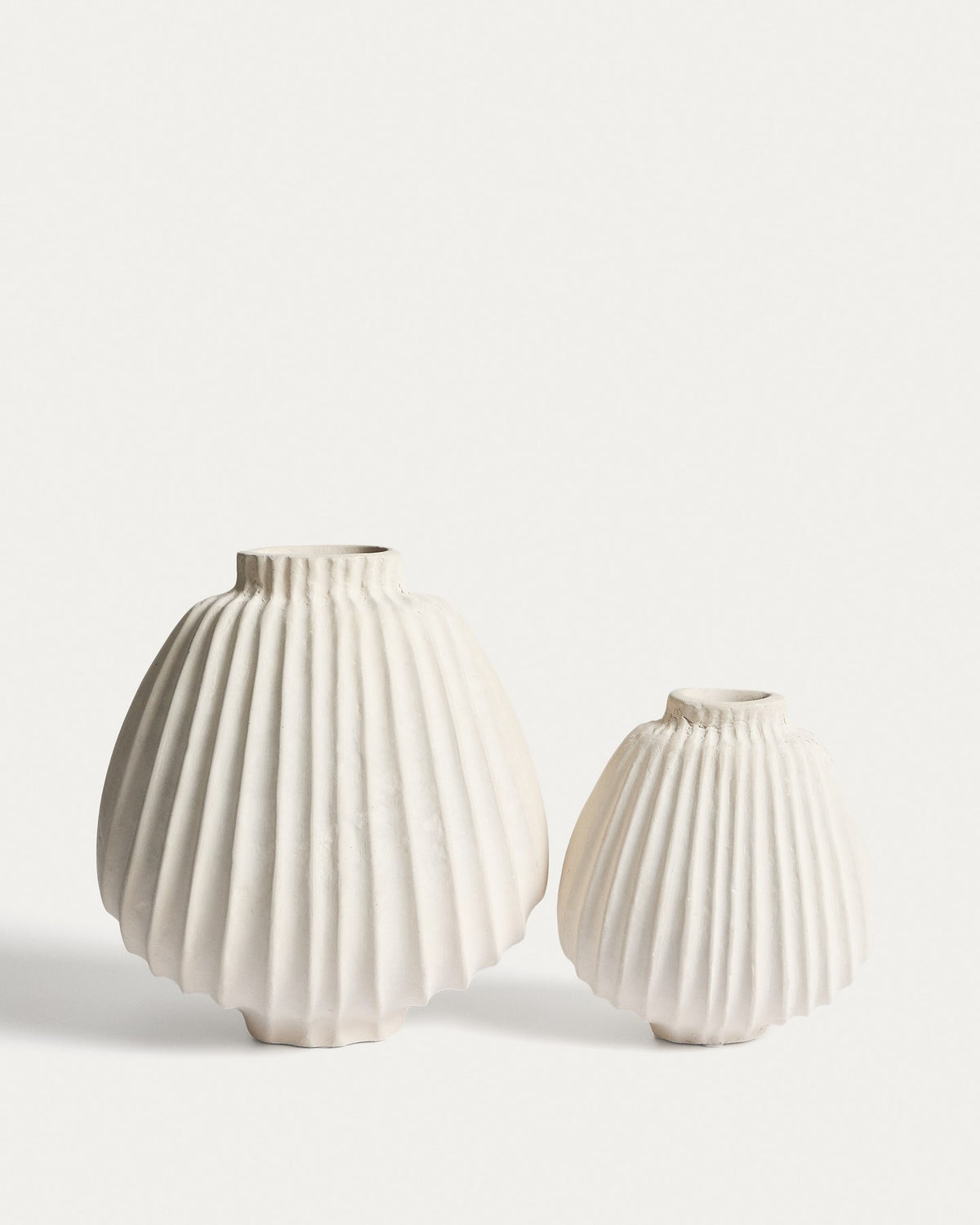 Handgefertigte Vase aus Pappmaché in der Farbe Ecru mit abgerundeter Form und feinen Relief-Linien auf der gesamten Oberfläche.