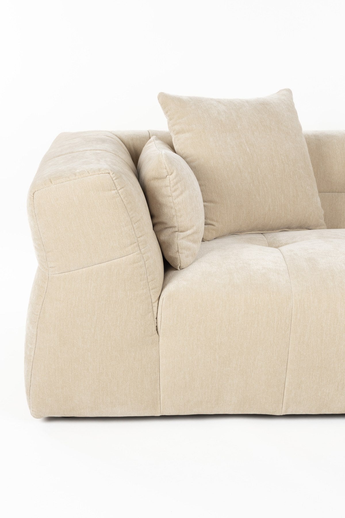 Beiges 5er Sofa Hodge von Dutchbone mit gestepptem Samtbezug, geschwungenen Armlehnen und leicht ausgestellten Rückenlehnen.