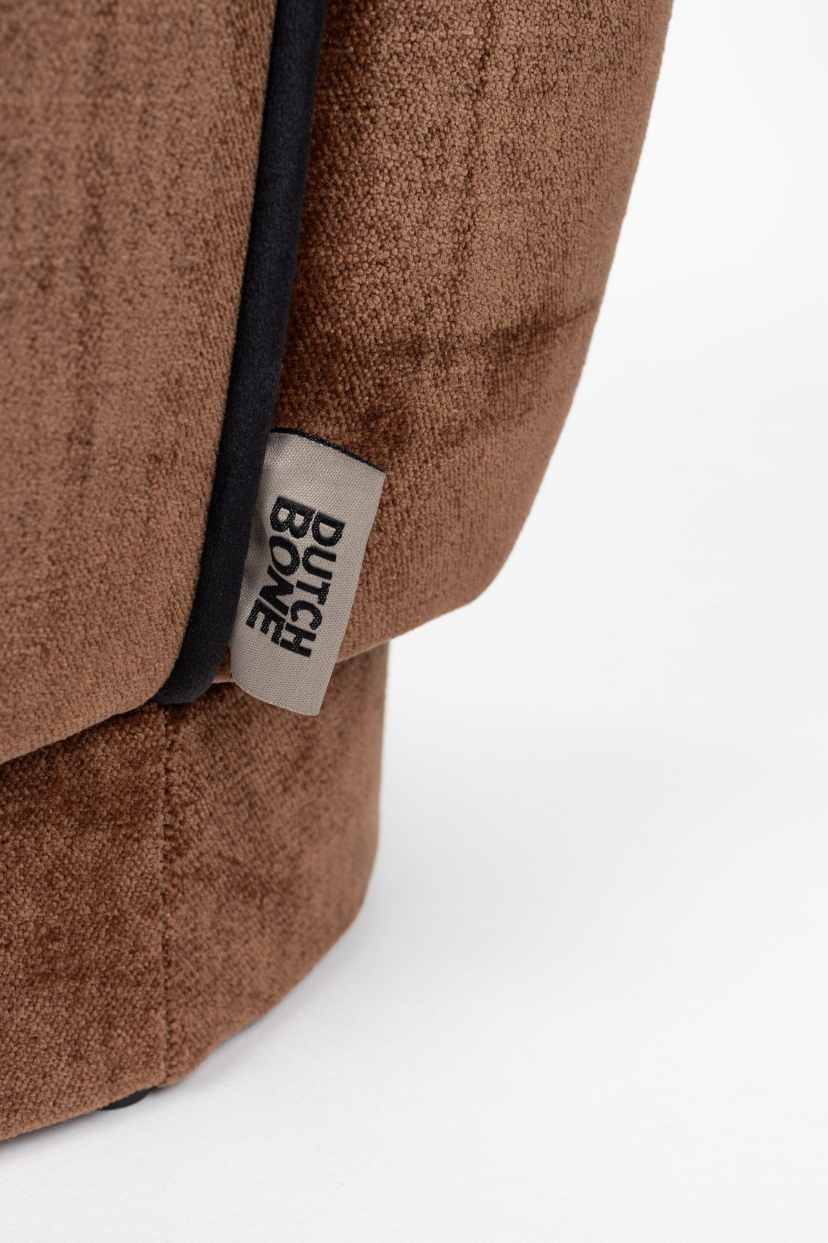 Runder Pouf mit dunkelbraunem Veloursbezug, gepolsterter Sitzfläche und dunklem Paspelrand, Hocker der Serie Donna von Dutchbone.
