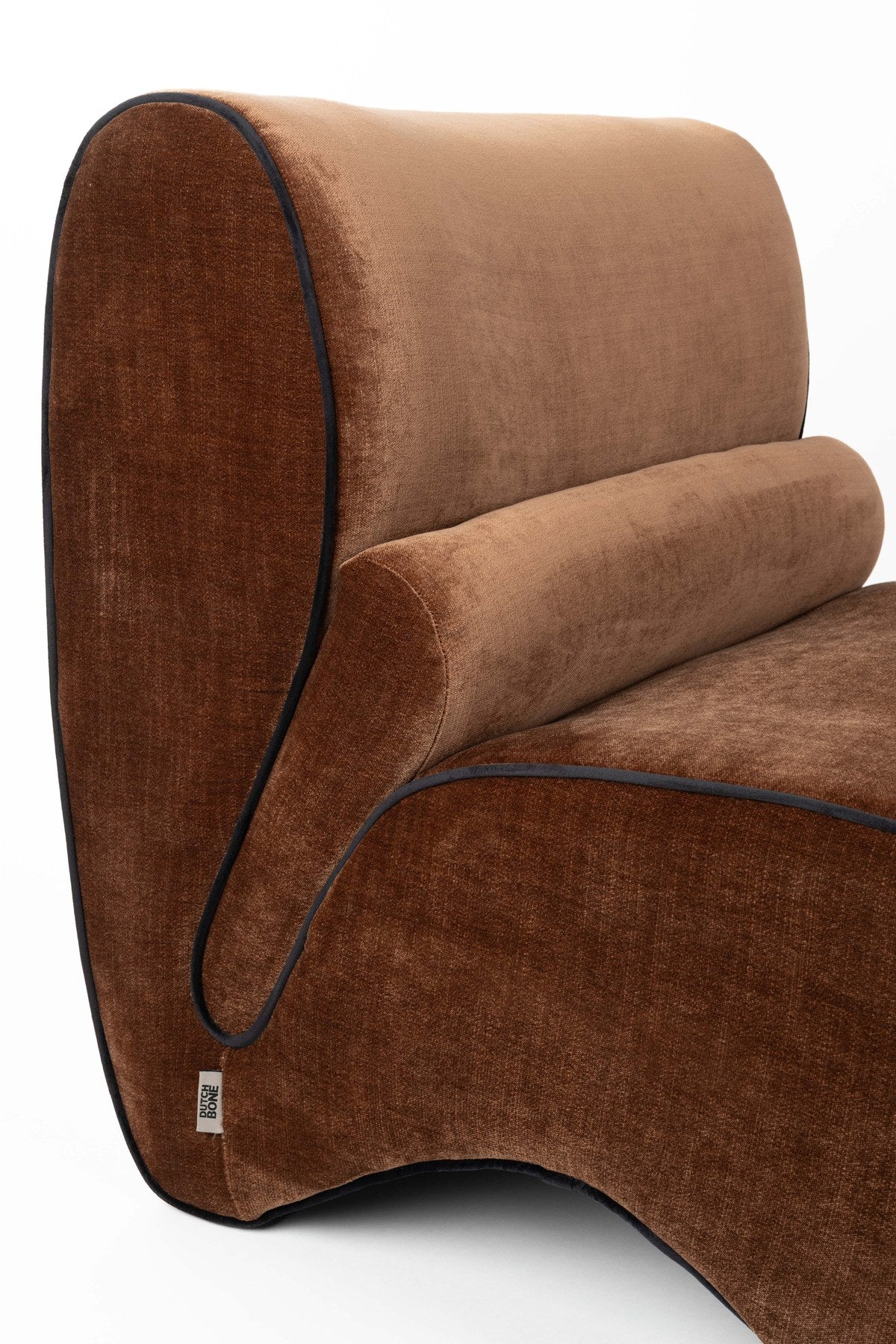 Dunkelbrauner Lounge Chair Donna von Dutchbone mit gepolsterter Sitzfläche, runden Formen und dunkler Paspel entlang der Rundungen.