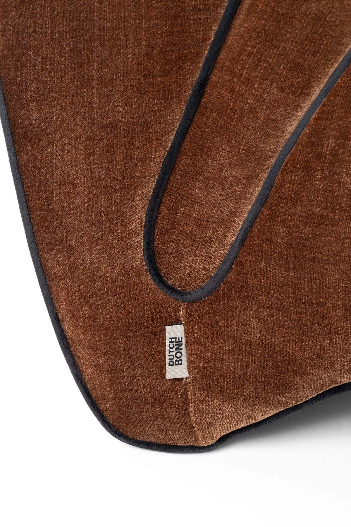 Dunkelbrauner Lounge Chair Donna von Dutchbone mit gepolsterter Sitzfläche, runden Formen und dunkler Paspel entlang der Rundungen.