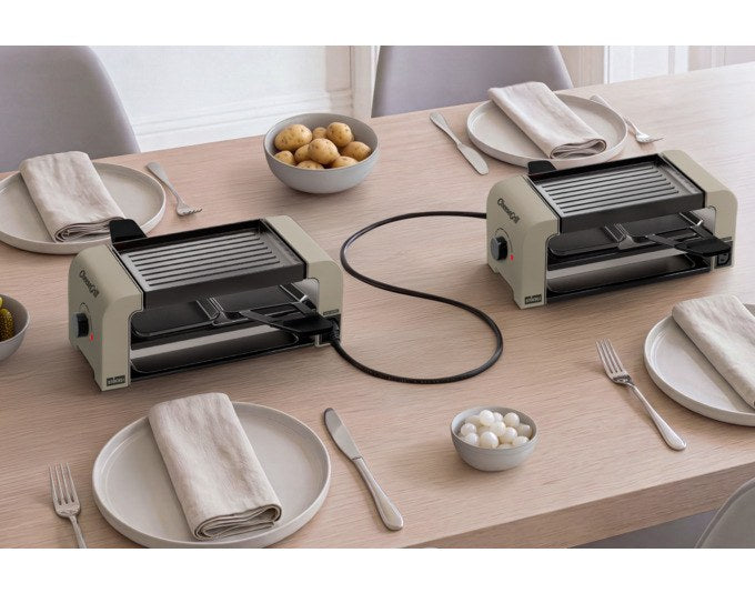 Tischgrill STÖCKLI CheeseGrill 2 Connect Set in Ivory Gold mit vier Pfännchen, Wende-Grillplatte und Parkdeck auf hellem Hintergrund.