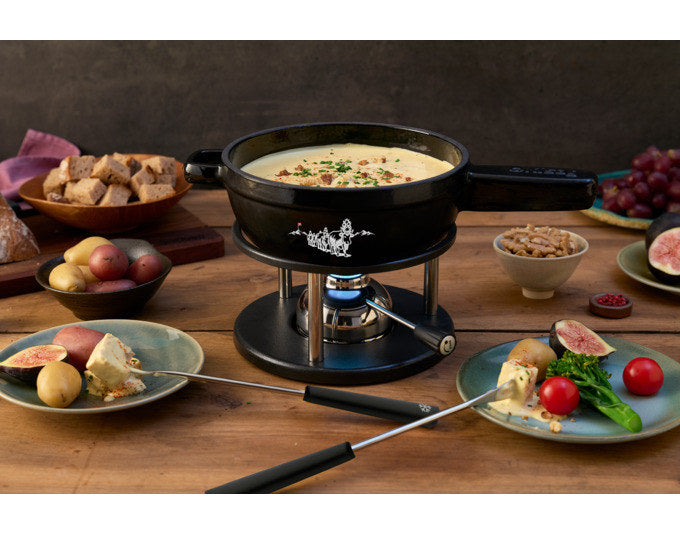 Schwarzes Fondue Set KISAG Alpsommer mit rundem Caquelon aus Gusseisen, Rechaud in Chrom/Silber und sechs Fonduegabeln auf weissem Hintergrund.