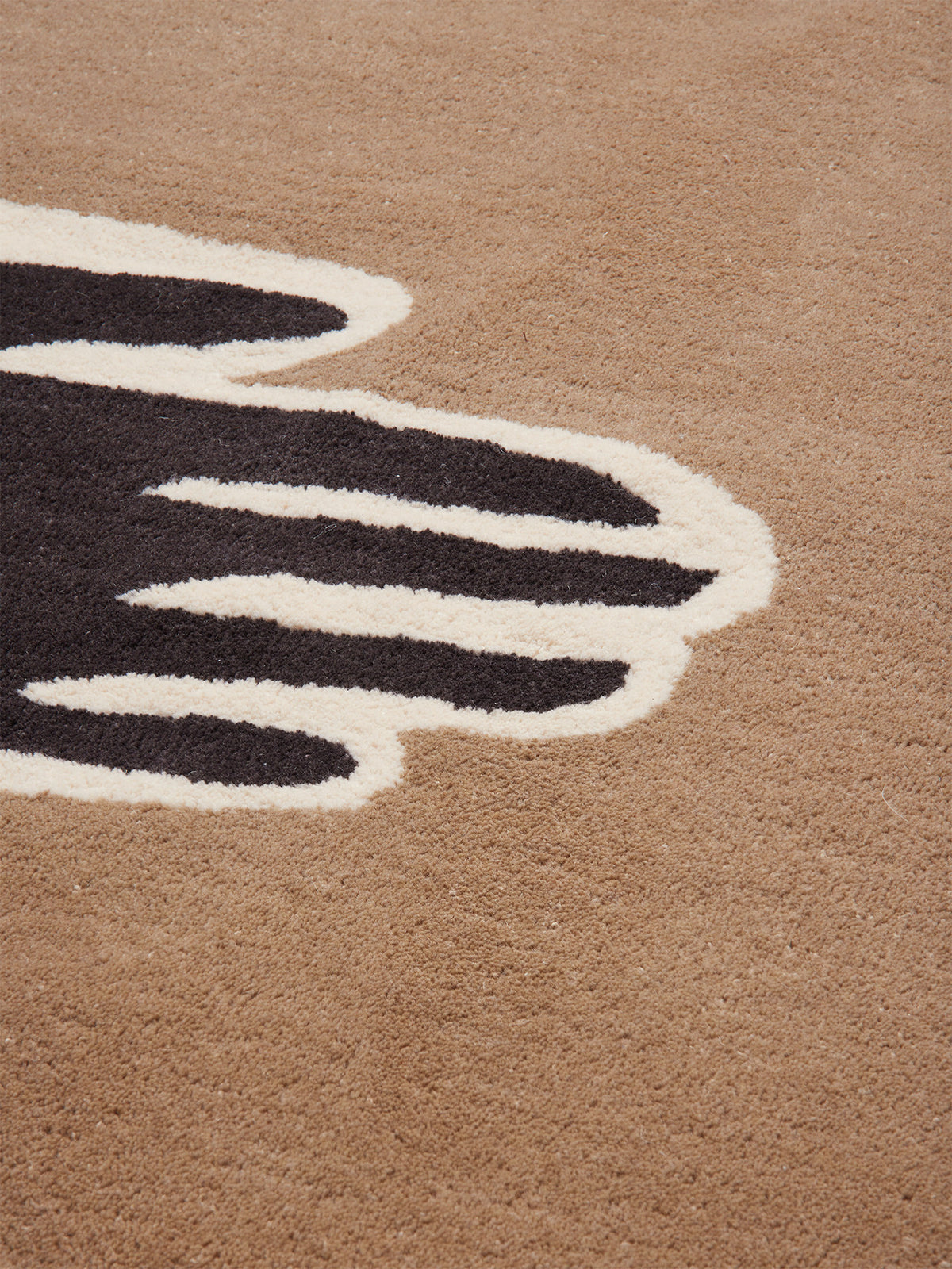 Getufteter Teppich Pose von Ferm Living in Dark Coffee/Offwhite mit stilisiertem Armmotiv, Vorderseite aus neuseeländischer Wolle, Rückseite aus Baumwolle.