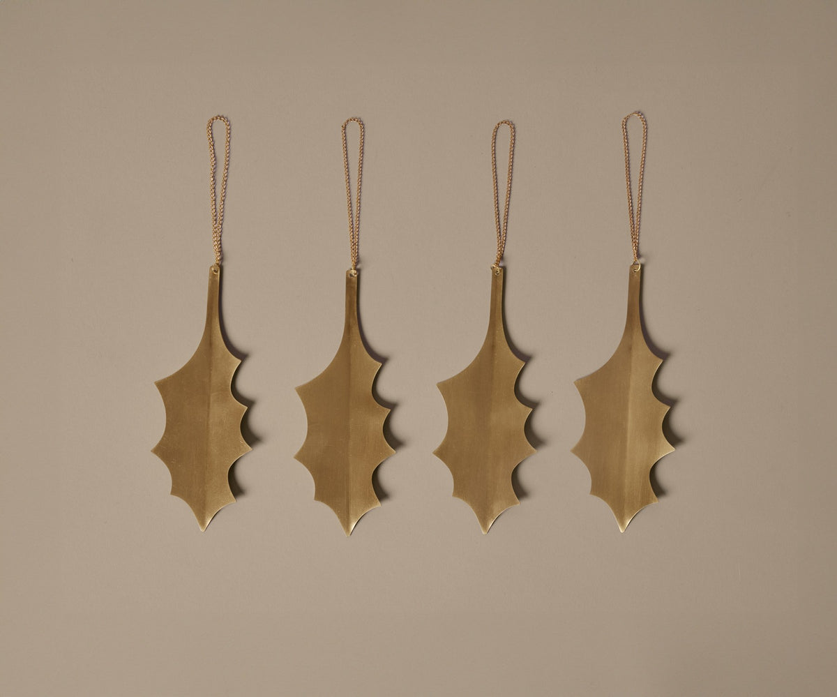 Set aus vier silberfarbenen Serviettenringen in Blattform aus versilbertem Massivmessing von Ferm Living, dekorativ auf weissem Untergrund arrangiert.