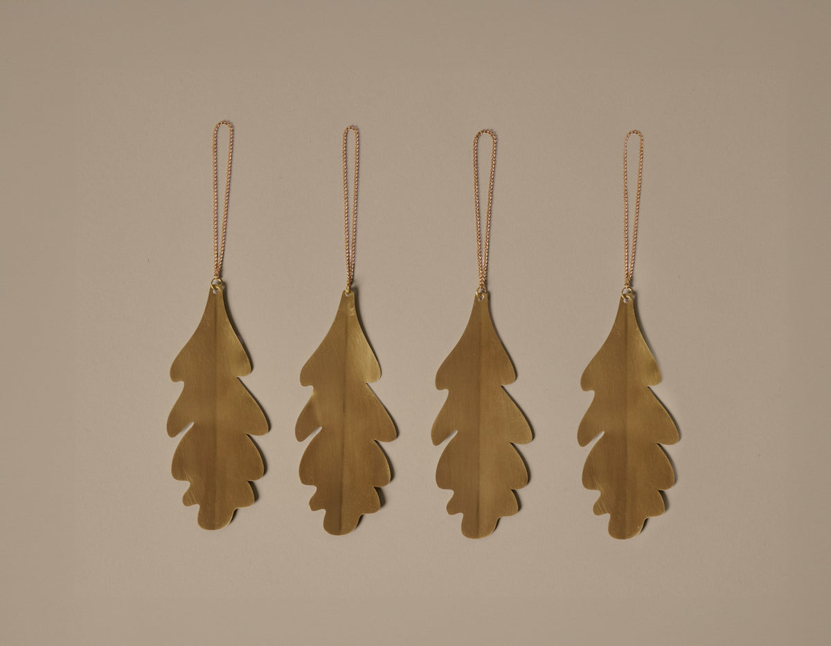 Vier silberne Eichenblatt-Ornamente aus versilbertem Massivmessing, blattförmig, glänzende Oberfläche, als Weihnachtsdekoration an Zweigen hängend.