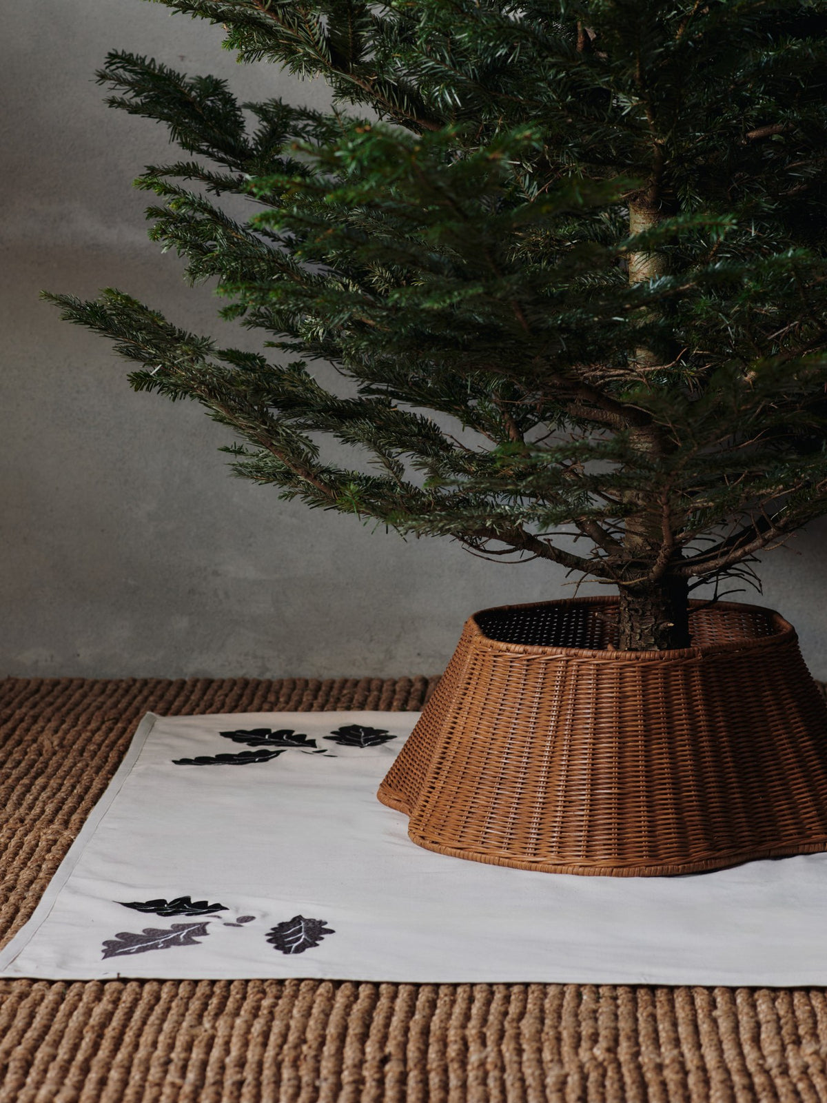 Zweiteiliger Baumrock aus handgeflochtenem Rattan mit Eisenstruktur im Inneren, natürliche Farbe, rund um den Weihnachtsbaum drapiert.