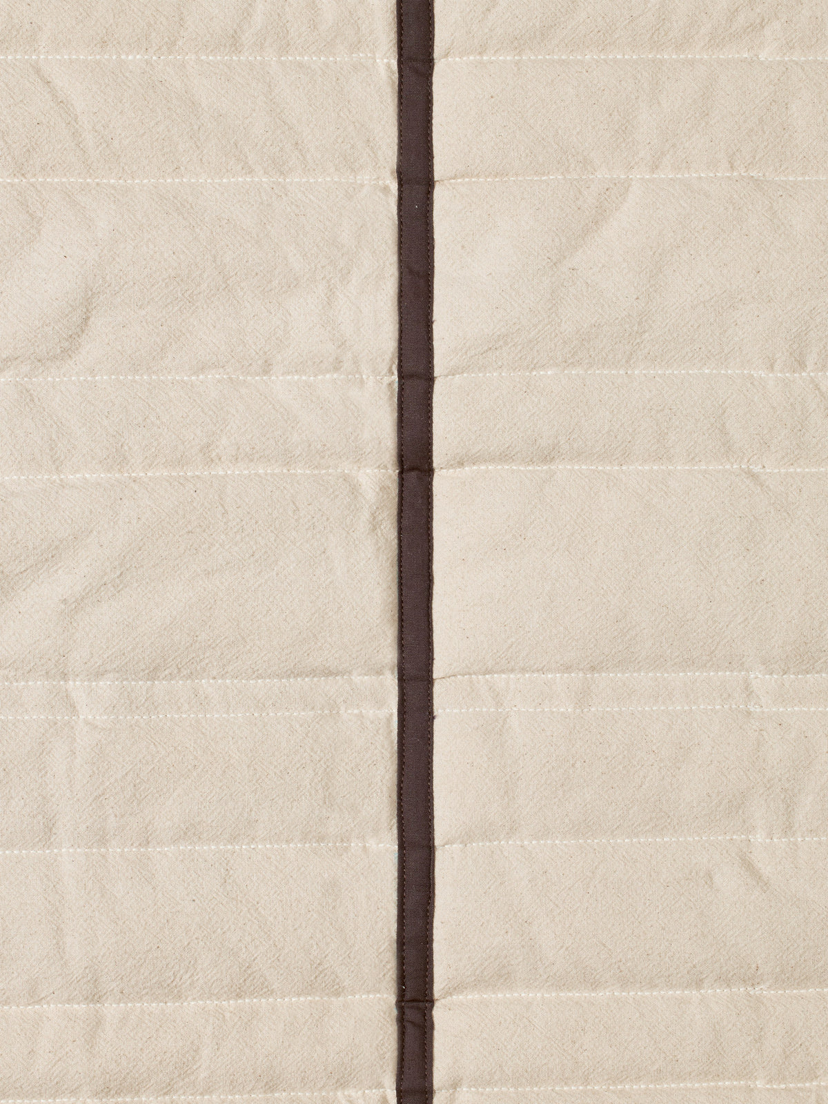 Gesteppte Tagesdecke Vari von Ferm Living aus Bio-Baumwolle in Natural mit Paspelierung in Dark Chocolate, auf Bett drapiert.