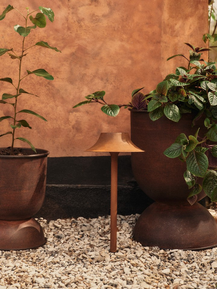 Moderner Hourglass Pflanzentopf in warmem Rostton von Ferm Living, perfekt für kreative Gartenarrangements und stilvolle Außenbereiche.