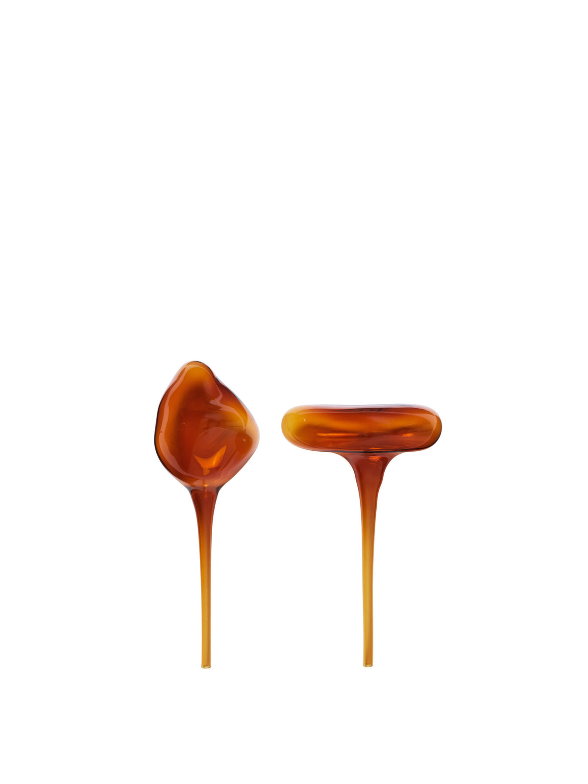 Zwei Wasserkugeln aus mundgeblasenem Glas in Amber von Ferm Living, organische Kugelform mit langem Stiel, stehend neben einem Pflanzentopf.