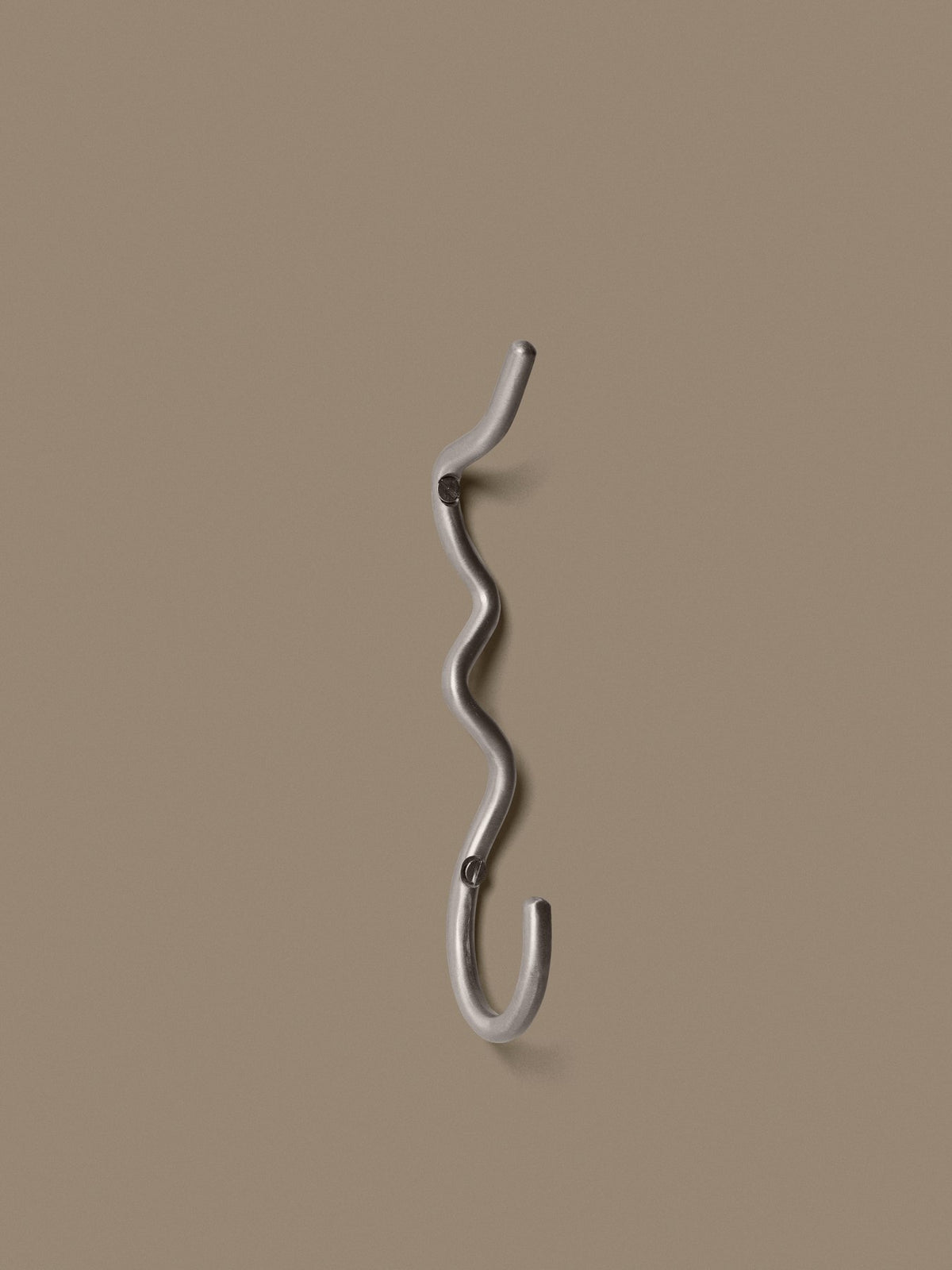 Curvature Haken von Ferm Living aus Edelstahl, handgefertigt mit geschwungener Form, zum Aufhängen von Handtüchern und Kleidung geeignet.