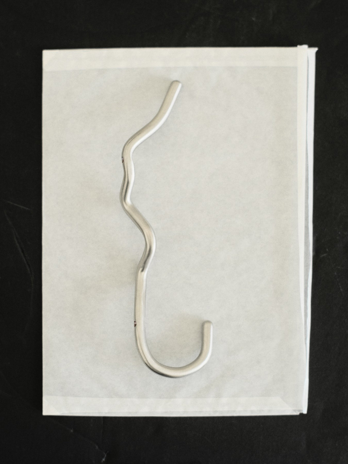 Curvature Haken von Ferm Living aus Edelstahl, handgefertigt mit geschwungener Form, zum Aufhängen von Handtüchern und Kleidung geeignet.