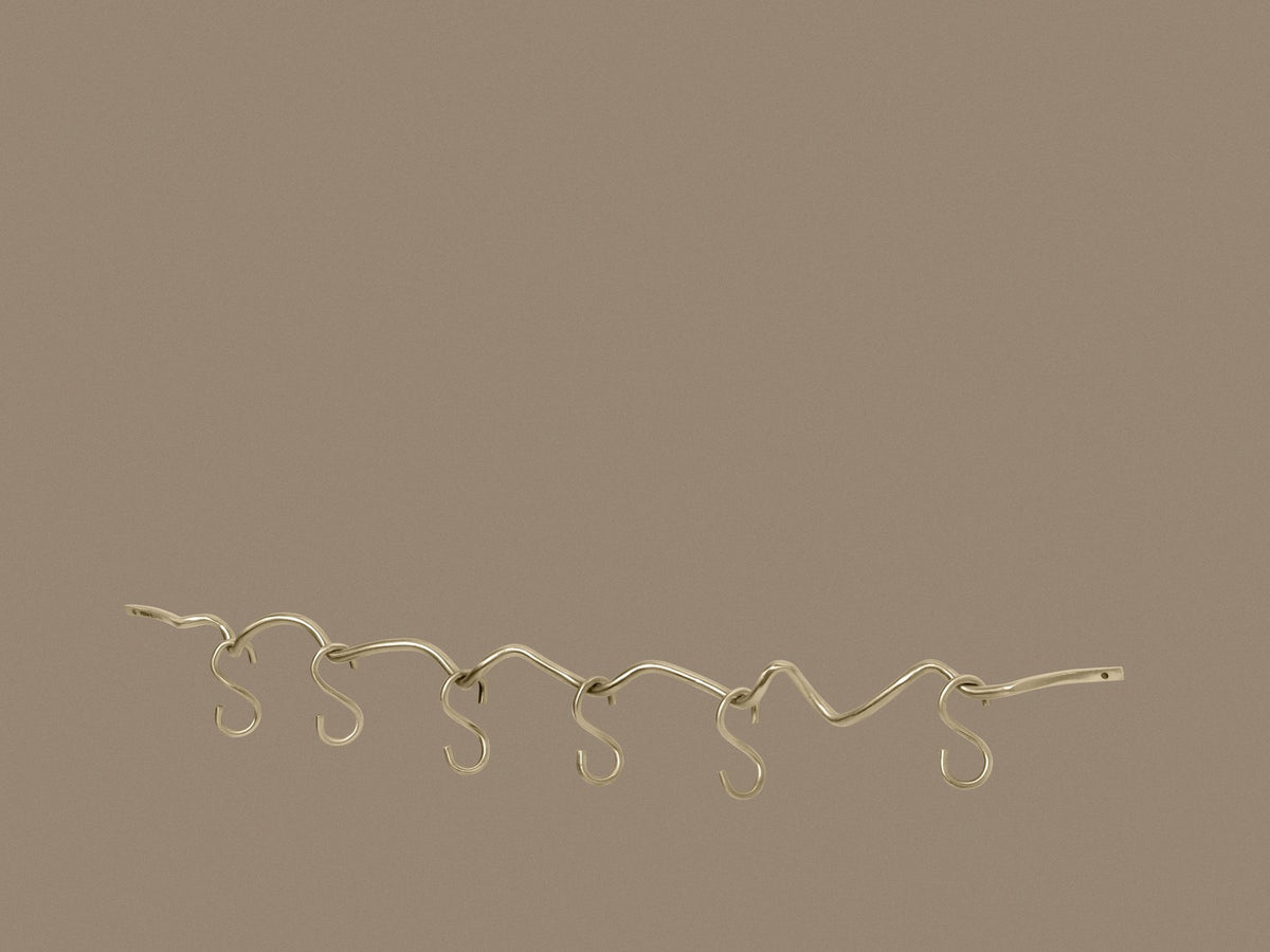Produktfoto der Curvature Hängestange von Ferm Living aus massivem Messing mit matter Politur, inklusive sechs Haken, geschwungene Form.