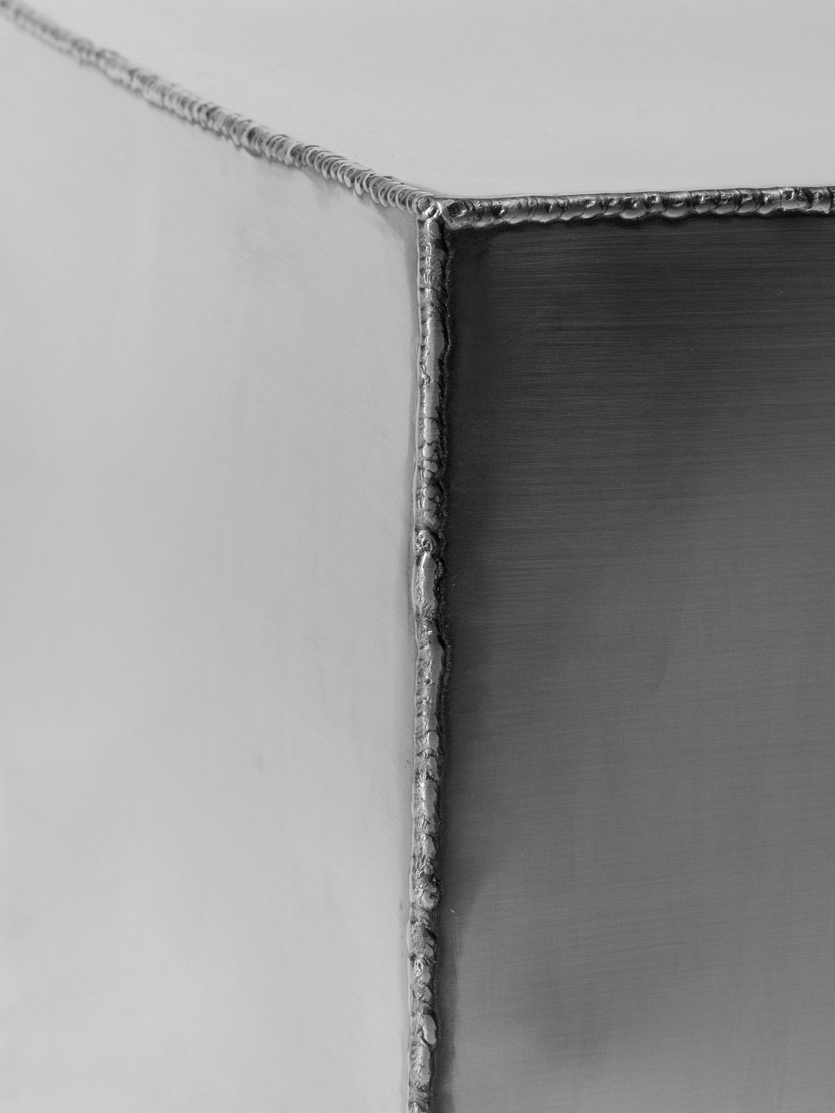 Ferra Couchtisch von Ferm Living aus gebürstetem Edelstahl mit sichtbaren, handverschweissten Kanten und leicht geschwungener Form.